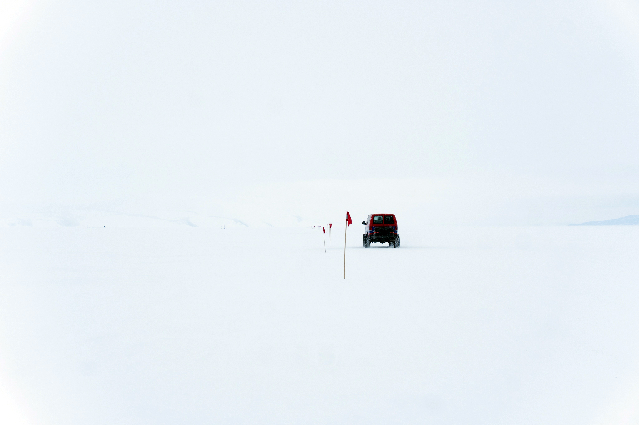 A van driving along a flagged snowy route.