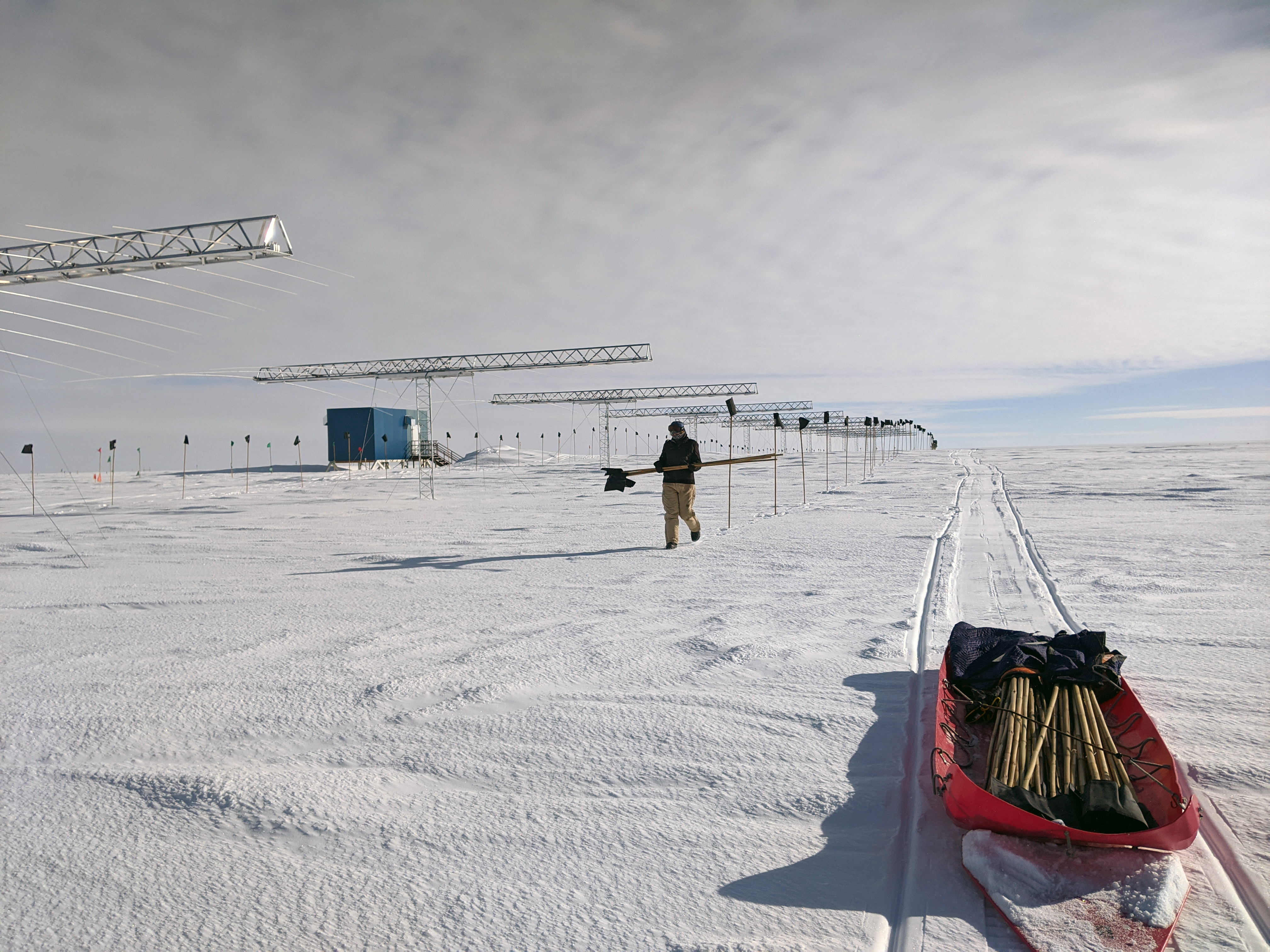 A person is placing black flags near a row of antennas.