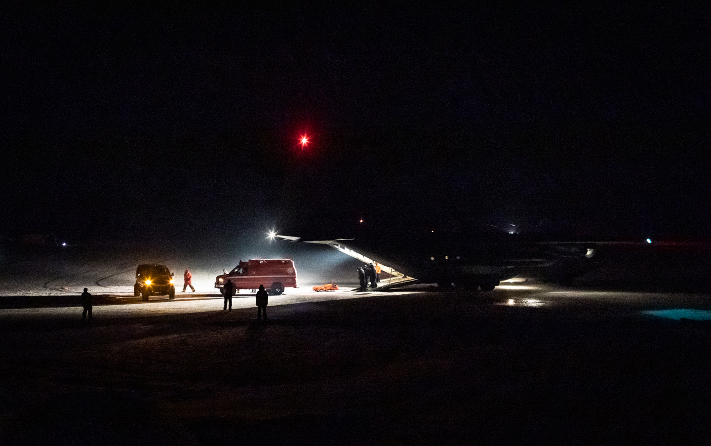 Emergency vehicles near a large airplane in the darkness of night.