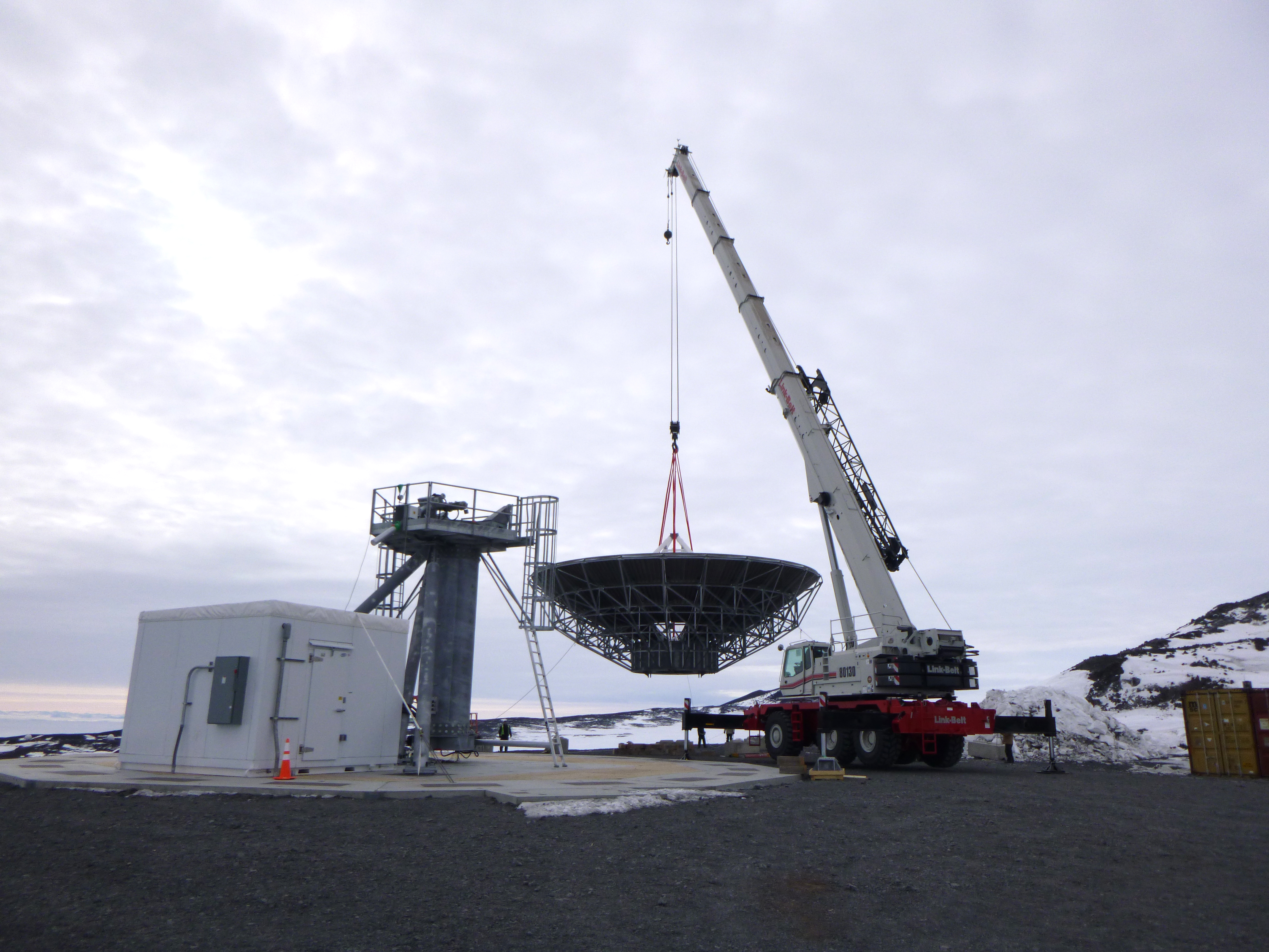 A crane moves a satellite communications dish.