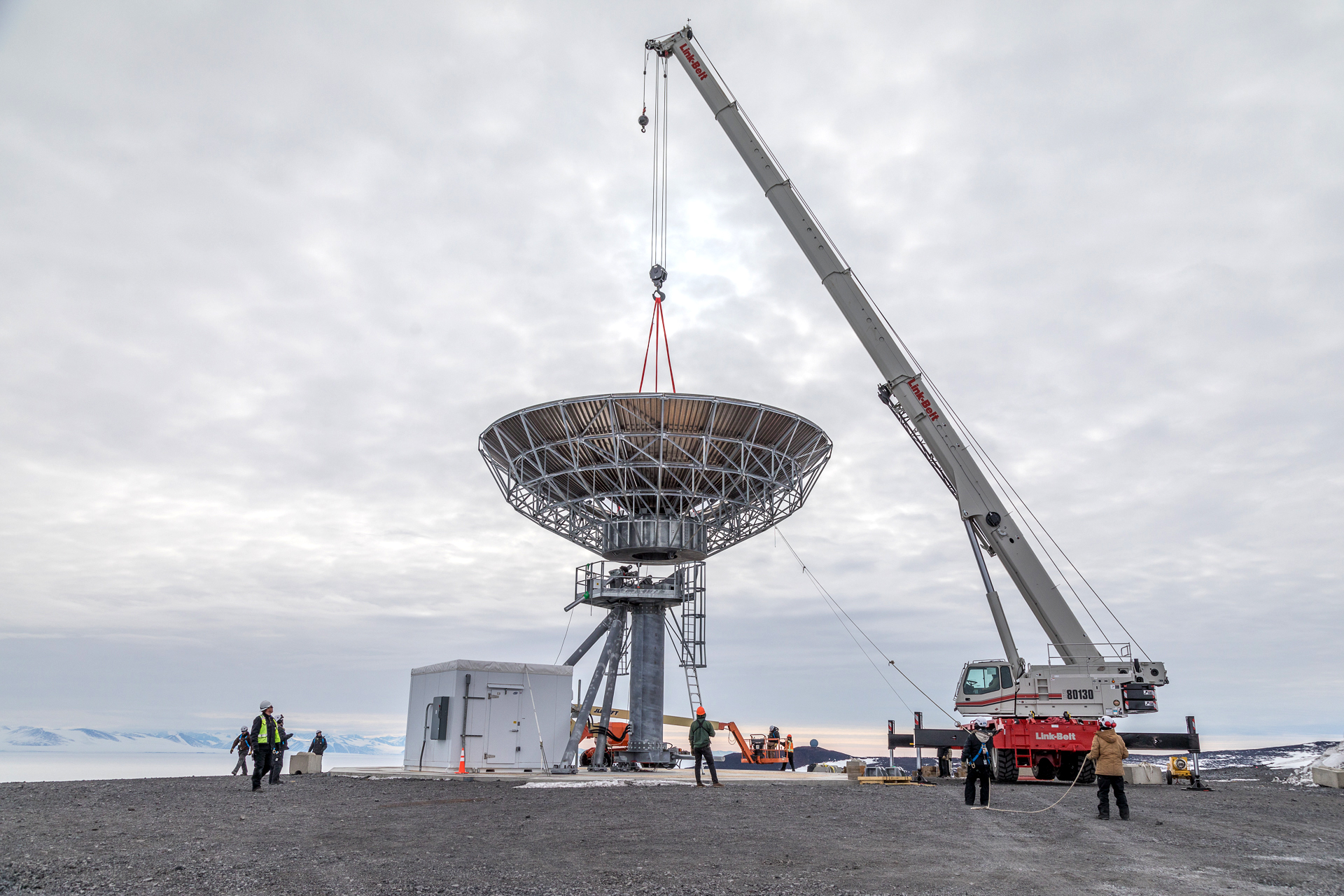 A crane moves a satellite communications dish.