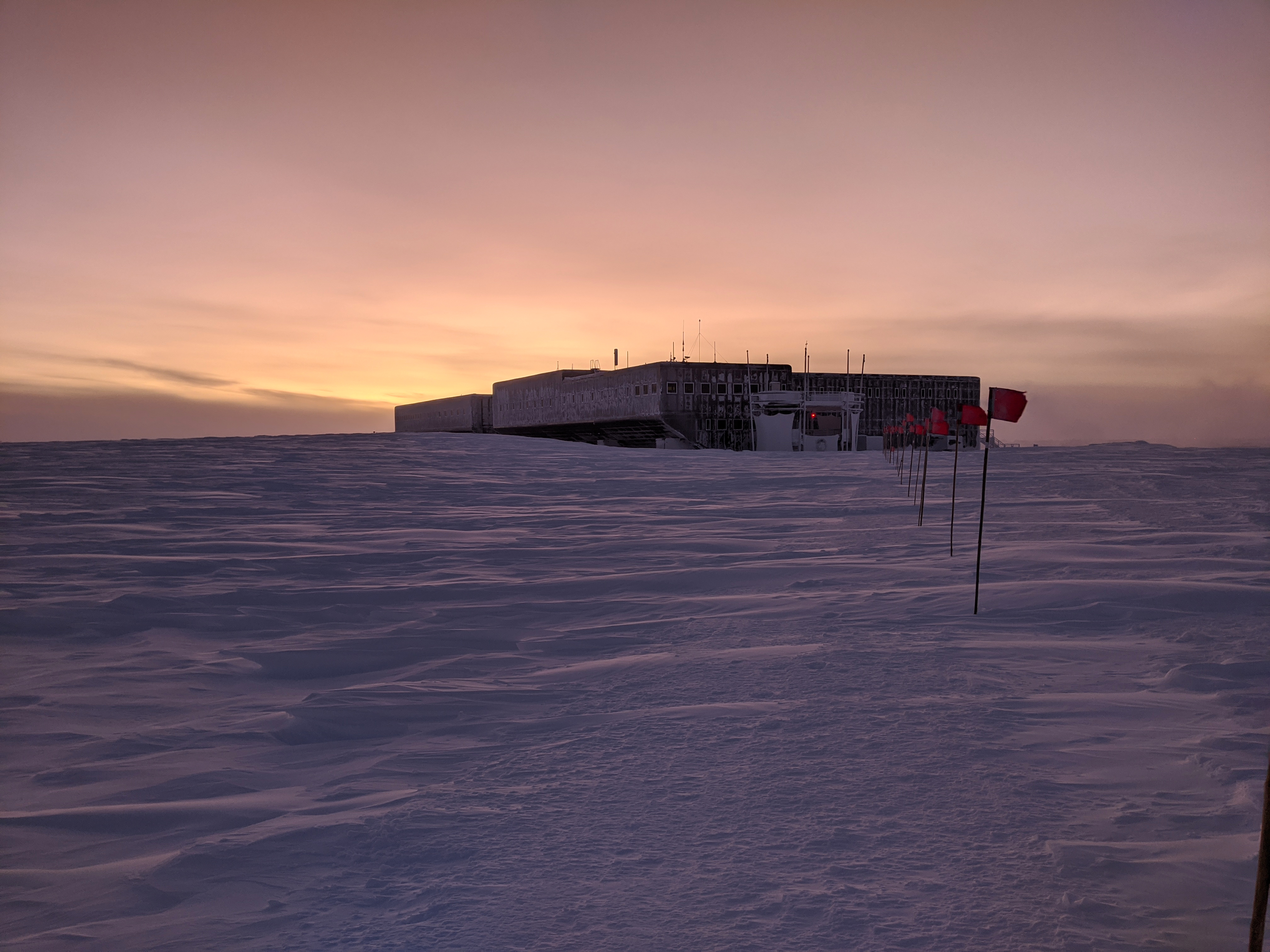 Twilight glow of an impending sunrise behind a large building.