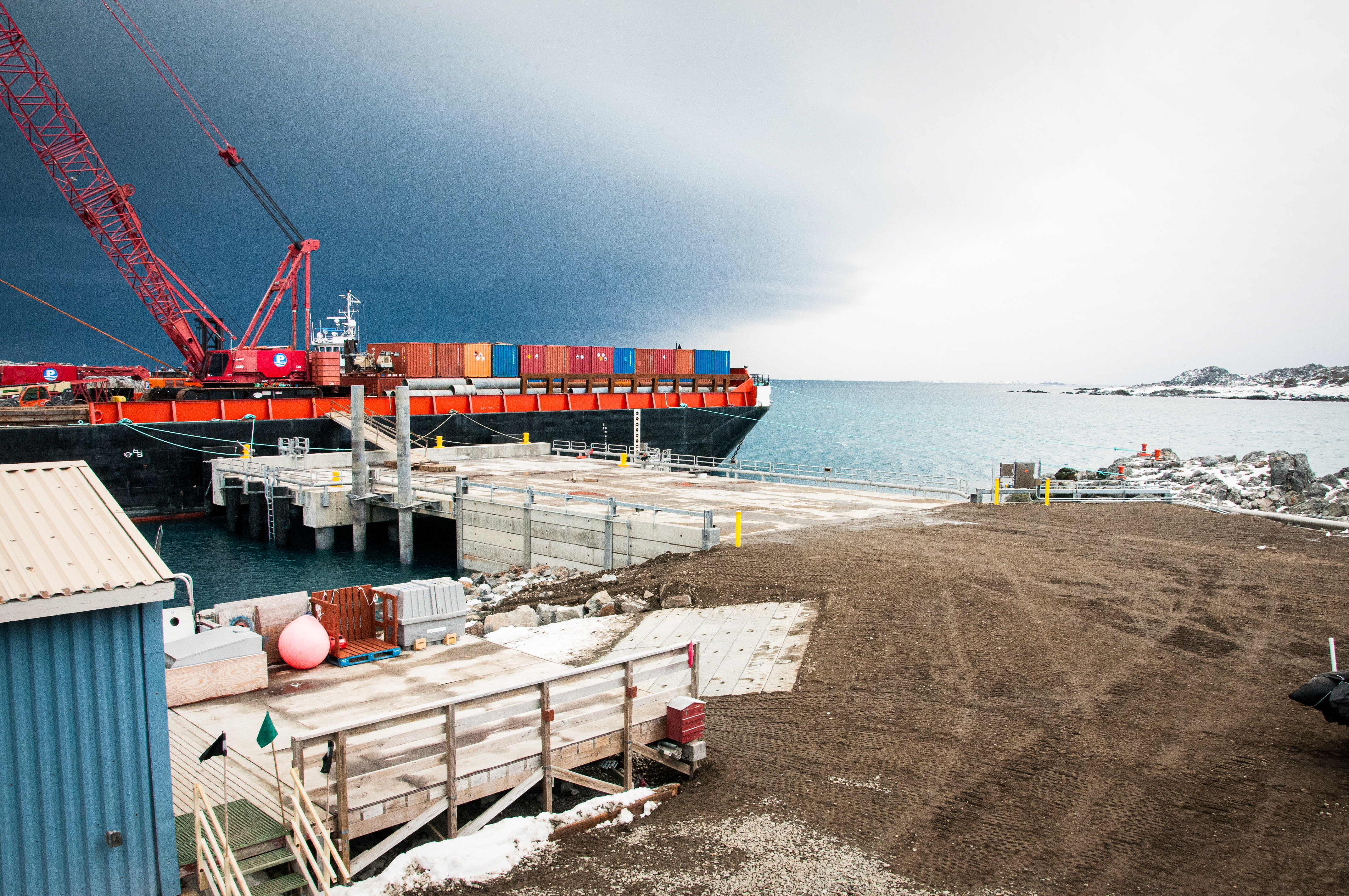 A pier with a barge and harbor in the background. 