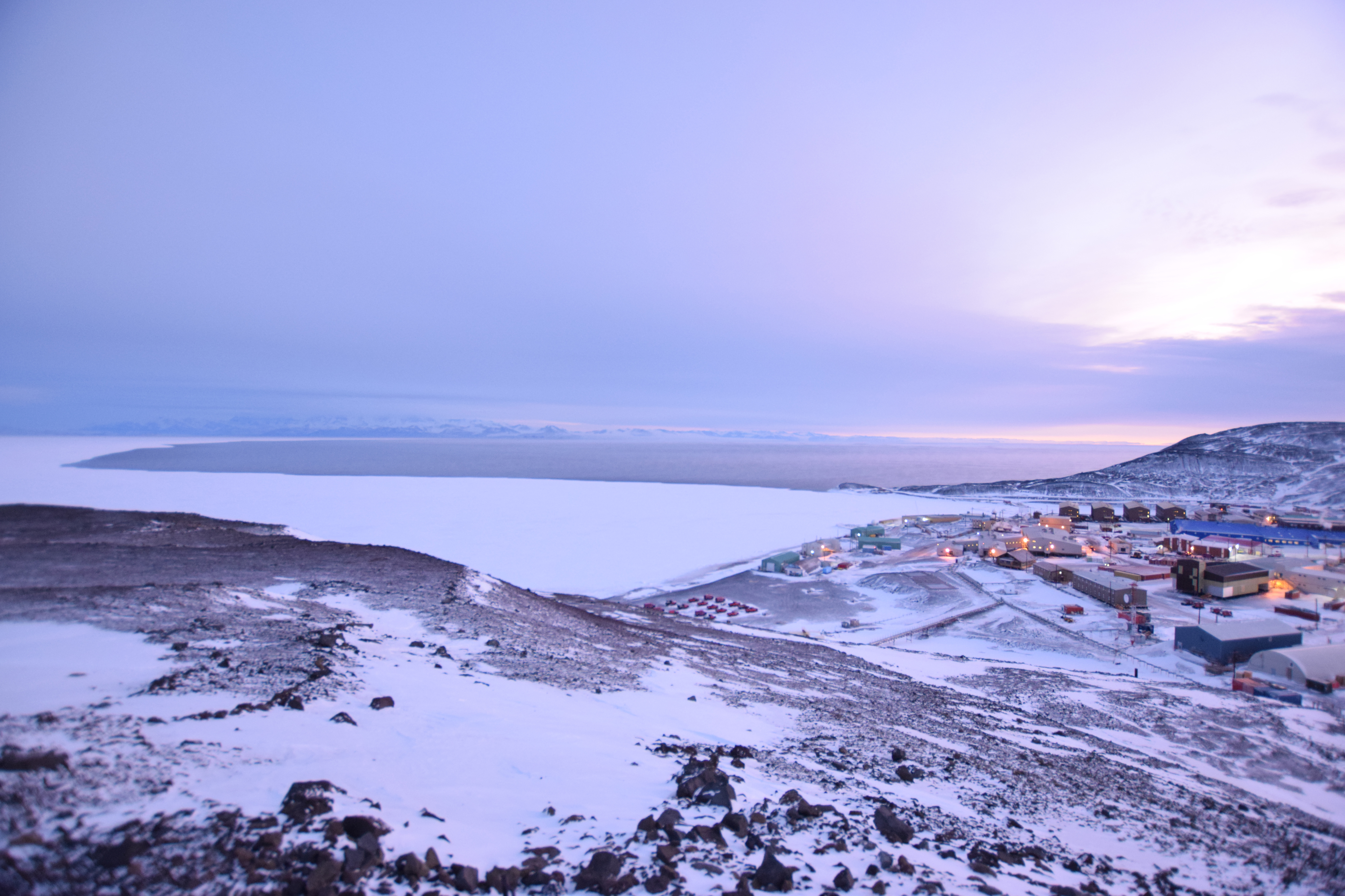 A hillside view of a town below, located next to the ocean.