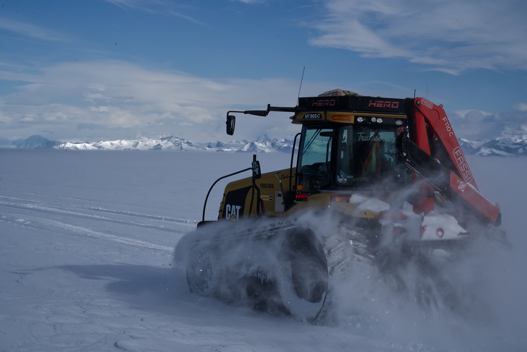 Red tractor travels on South Pole Traverse with mountains in background