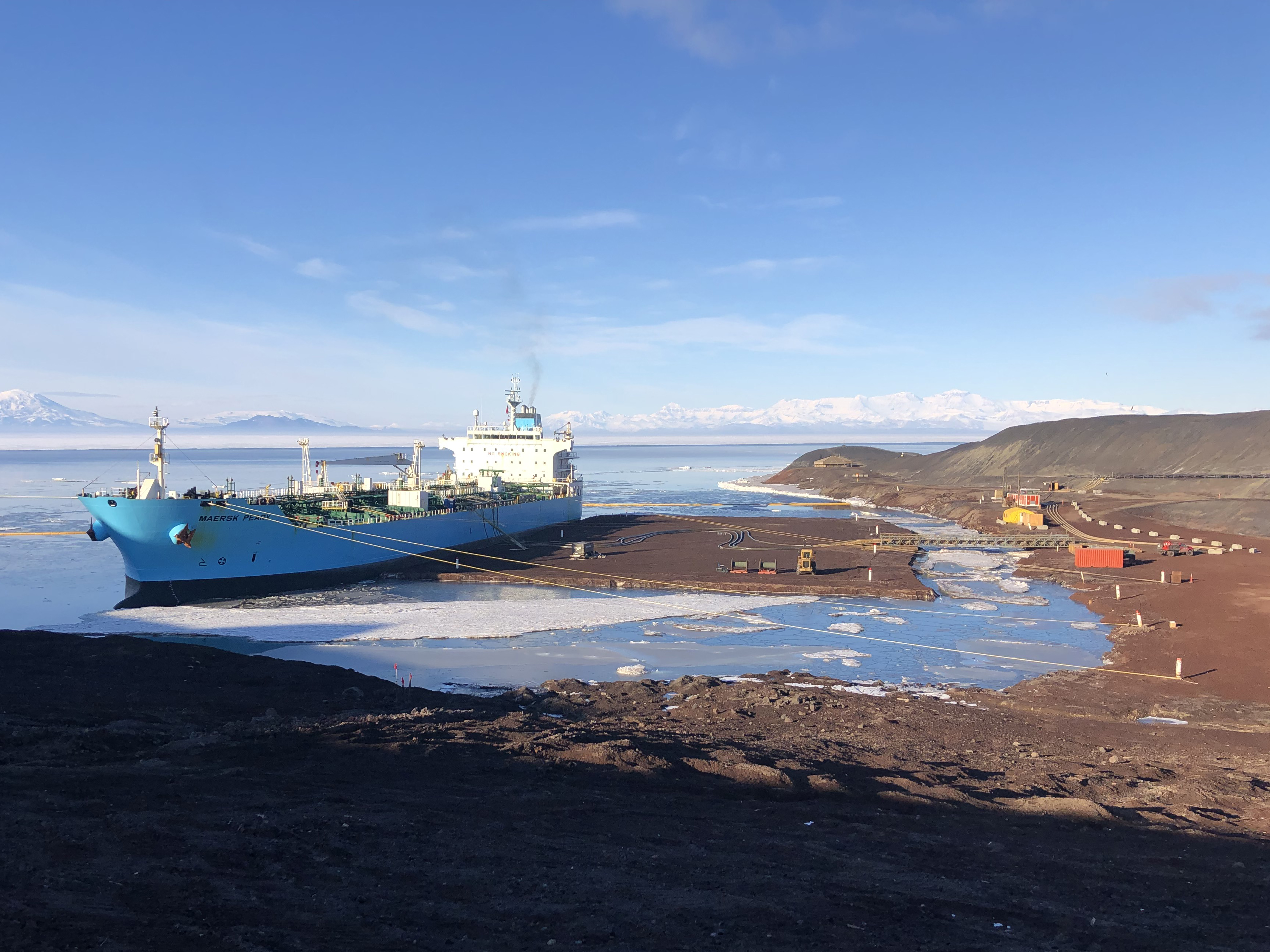 A blue fuel tanker ship tied to land bollards.