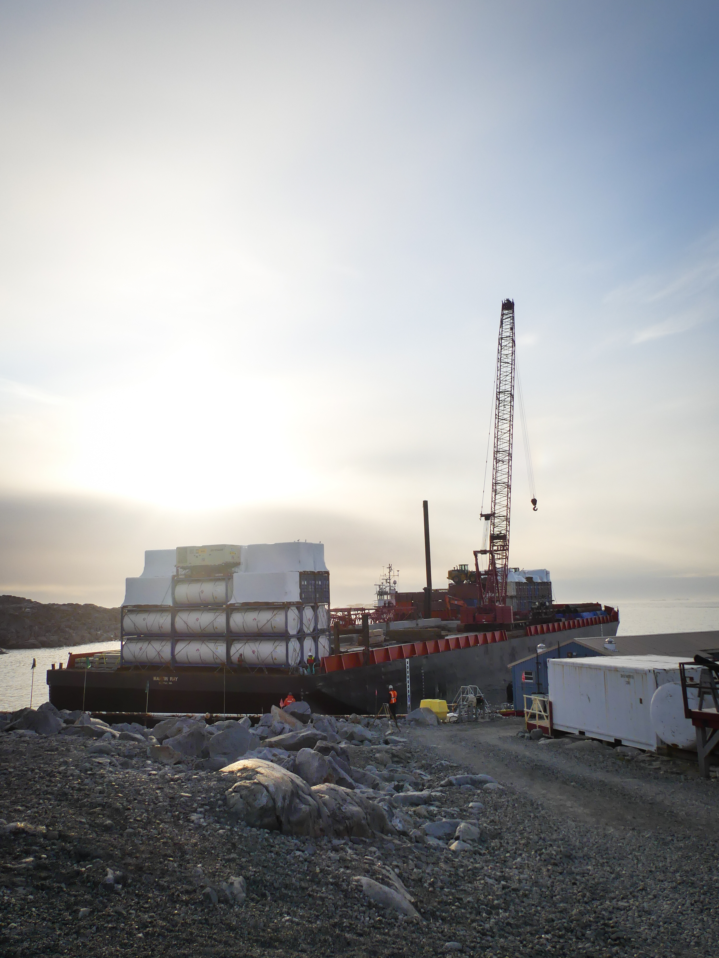 A barge tied up to a dirt pier. 