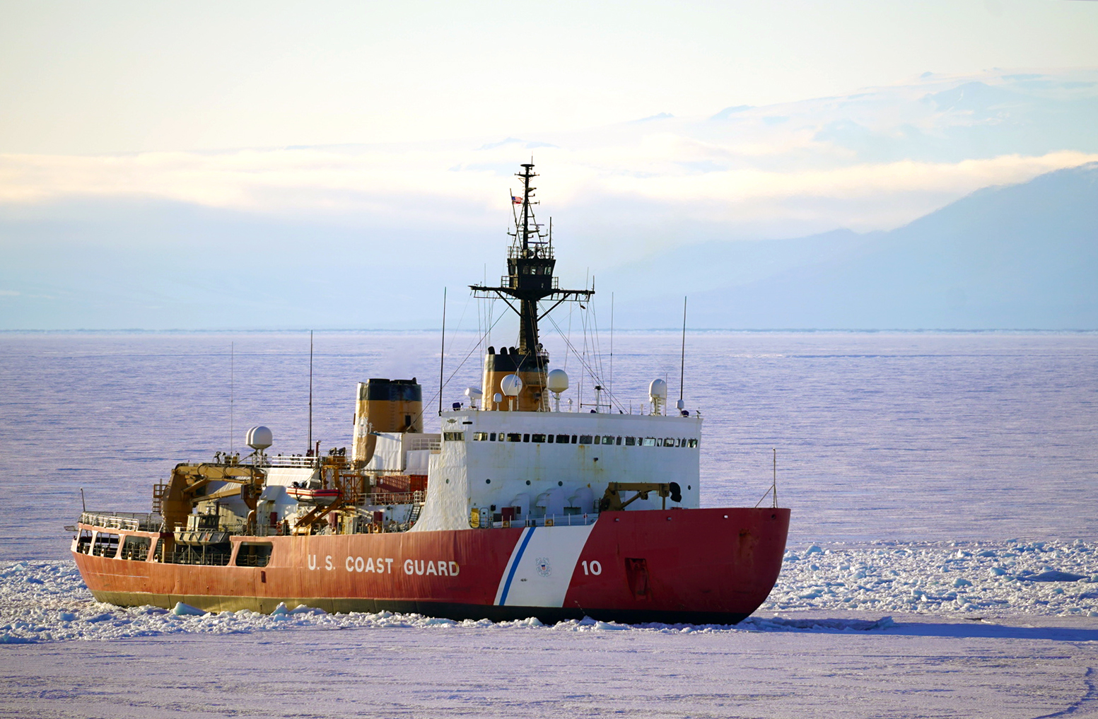 A red and white ship in ice-choked water.