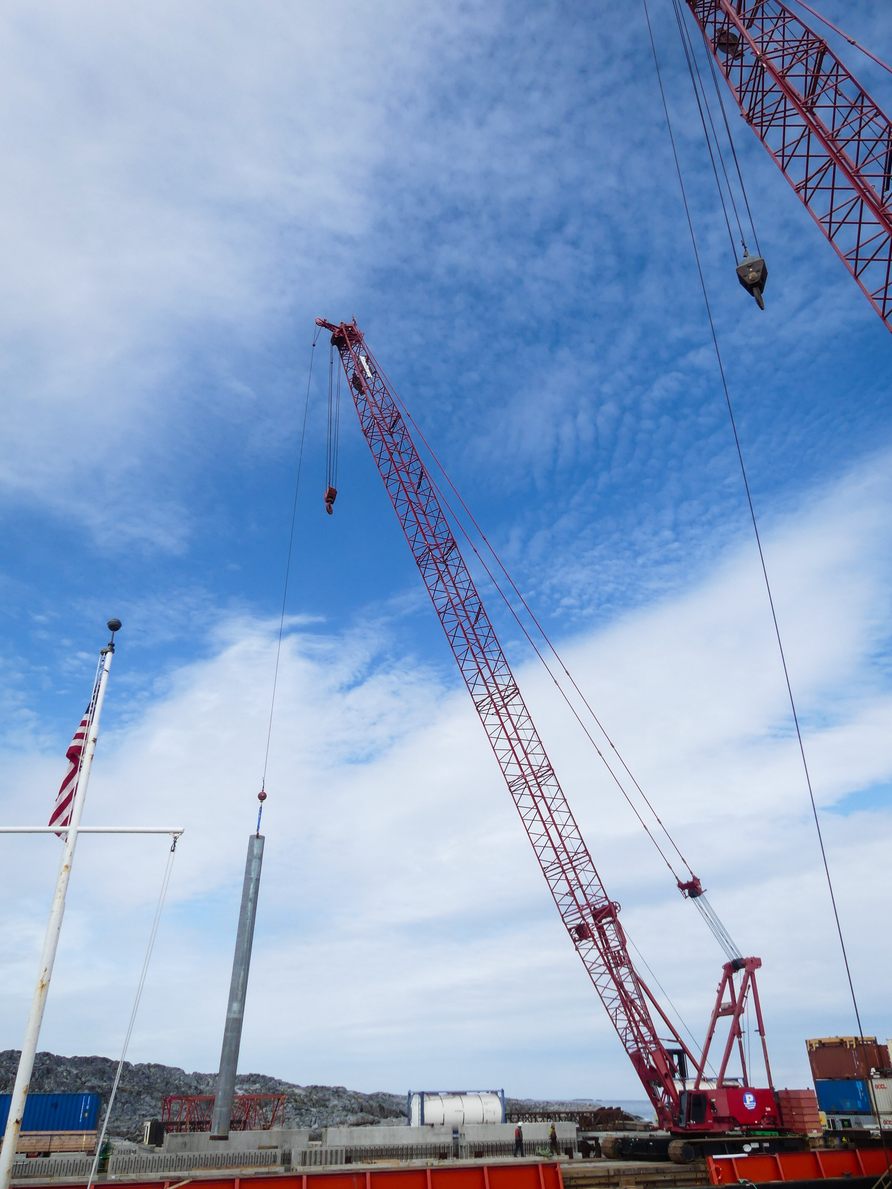 A crane lifts a steel pylon. 