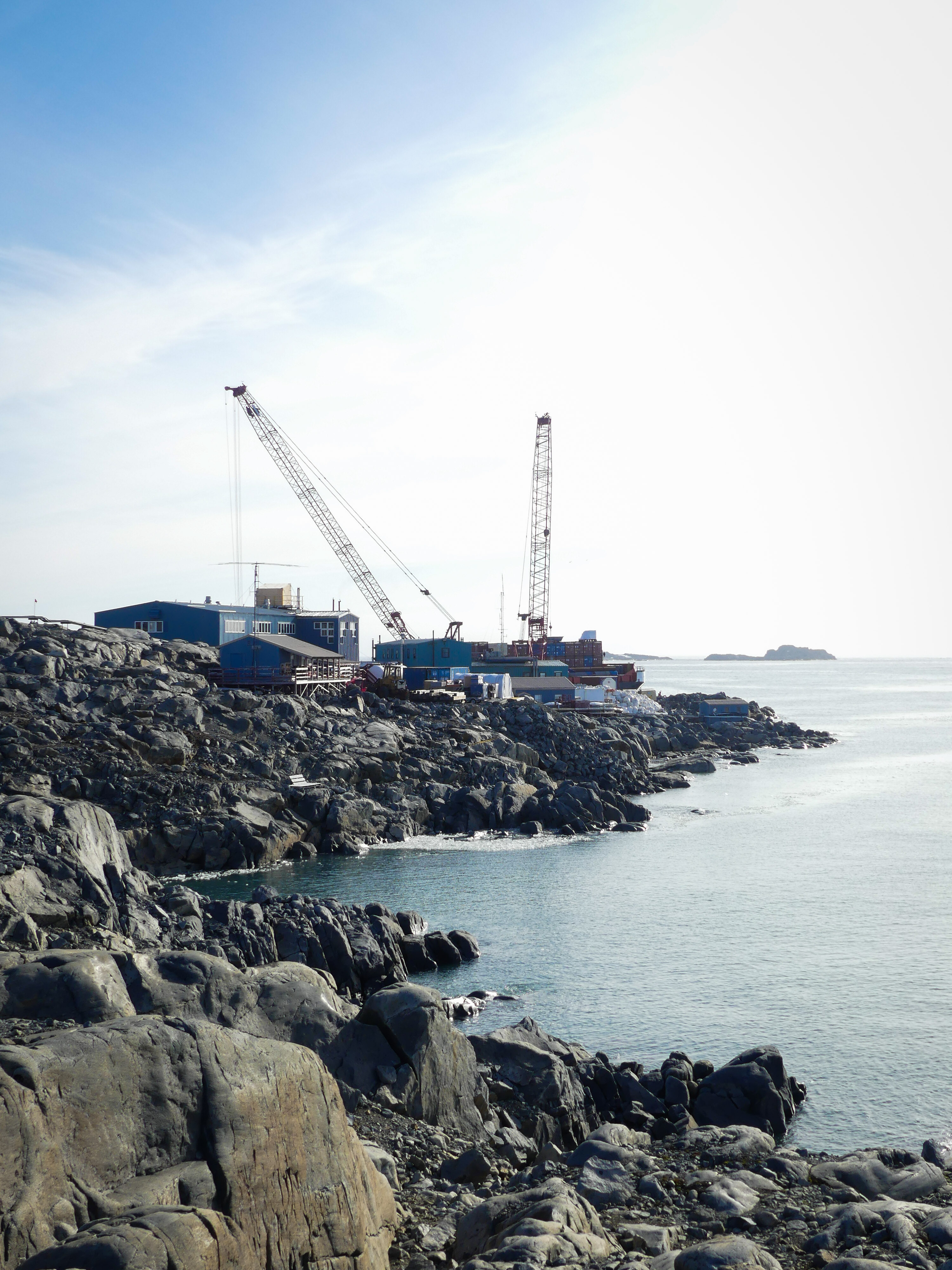 A rocky shore with construction cranes and buildings in the background. 