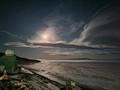 A bright moon illuminates a night landscape.