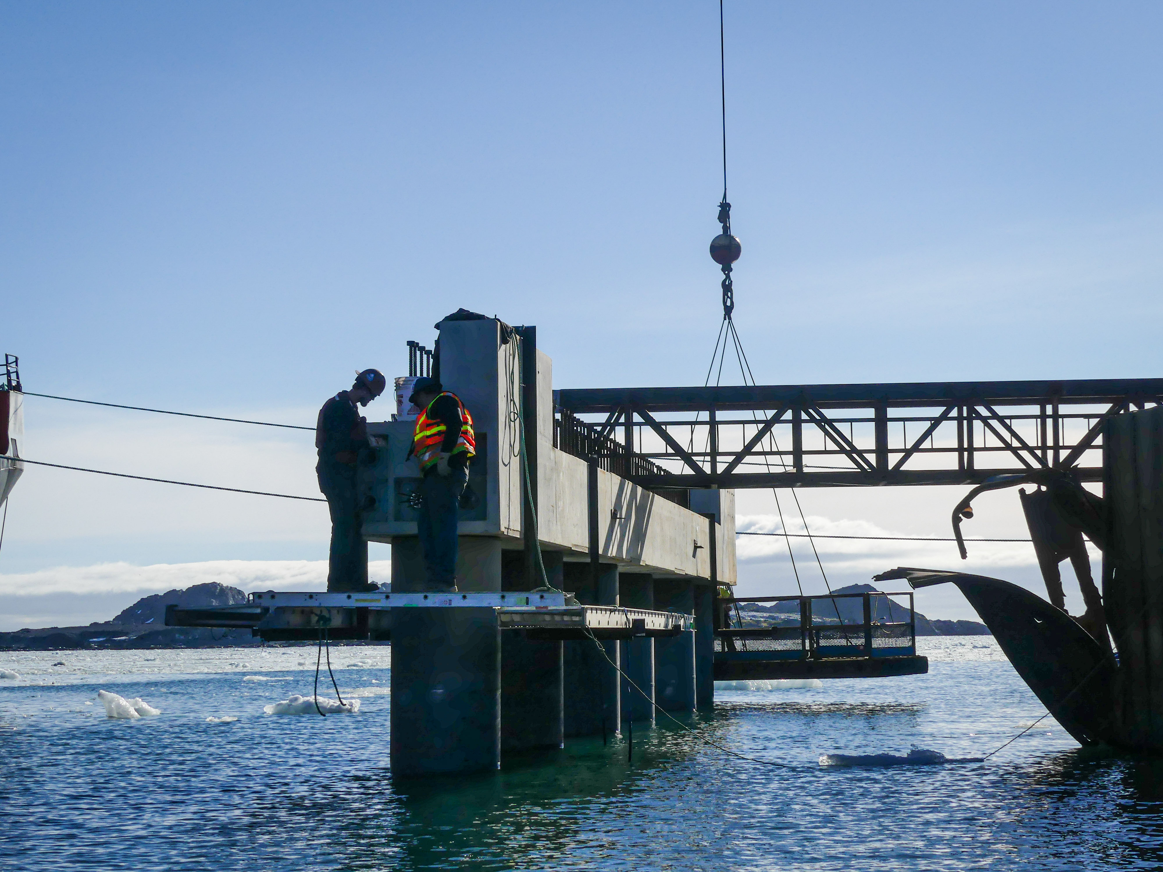 Construction workers standing on top of a concrete pier. 