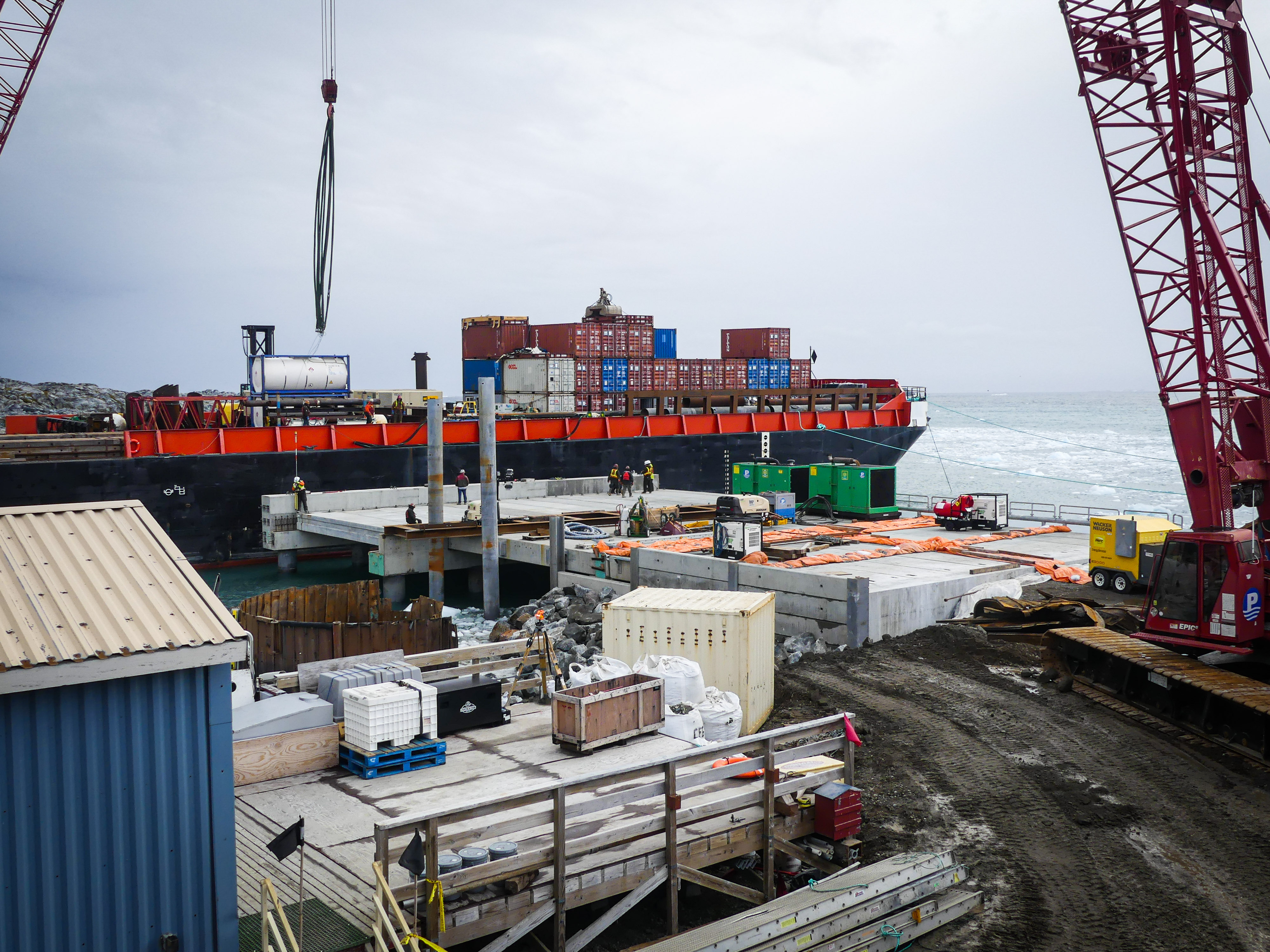 A concrete pier and construction site with a barge in the background. 