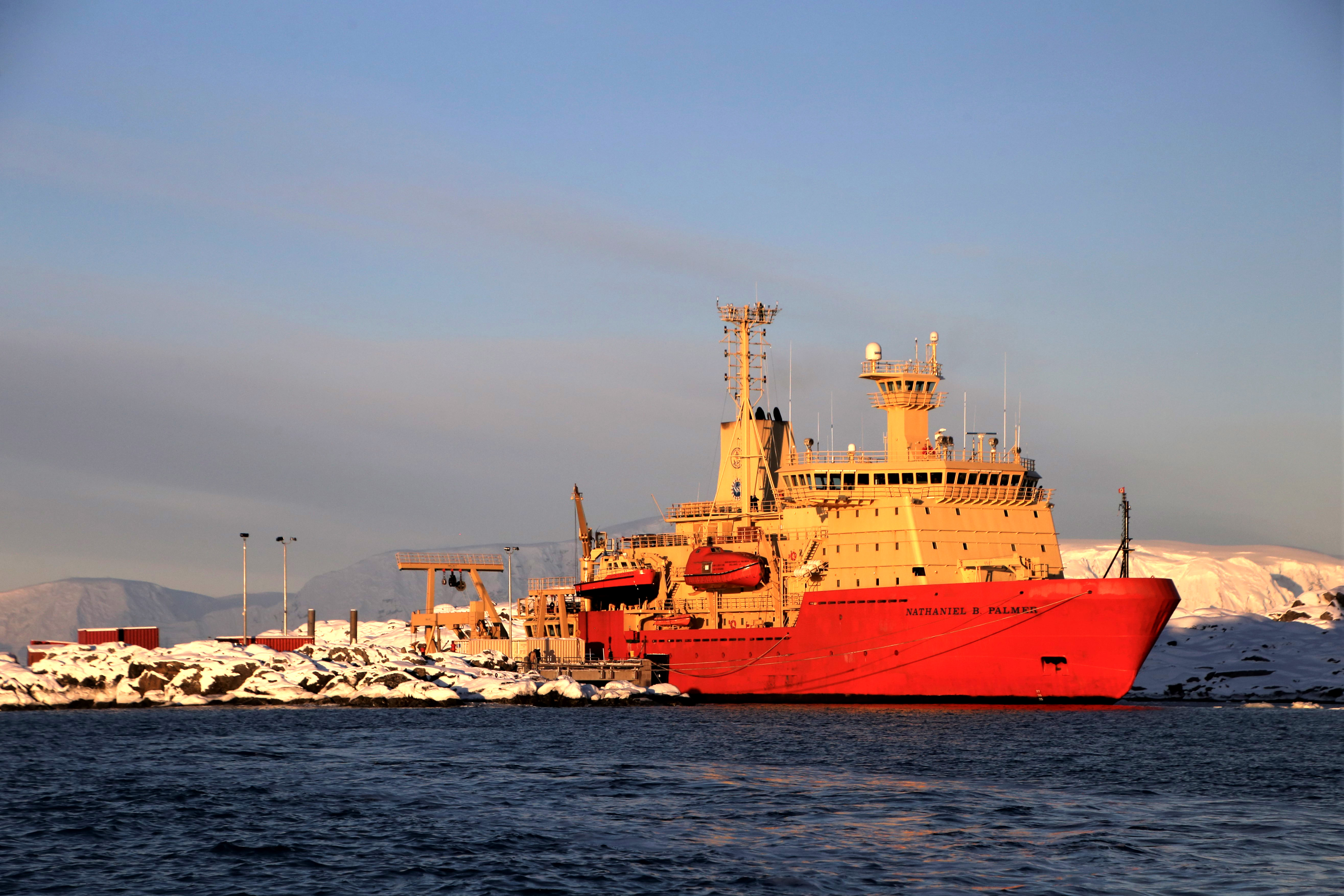 An orange and gold ship docked at a pier.