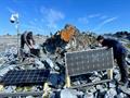 Two men disassemble solar panels and other equipment on rocky terrain