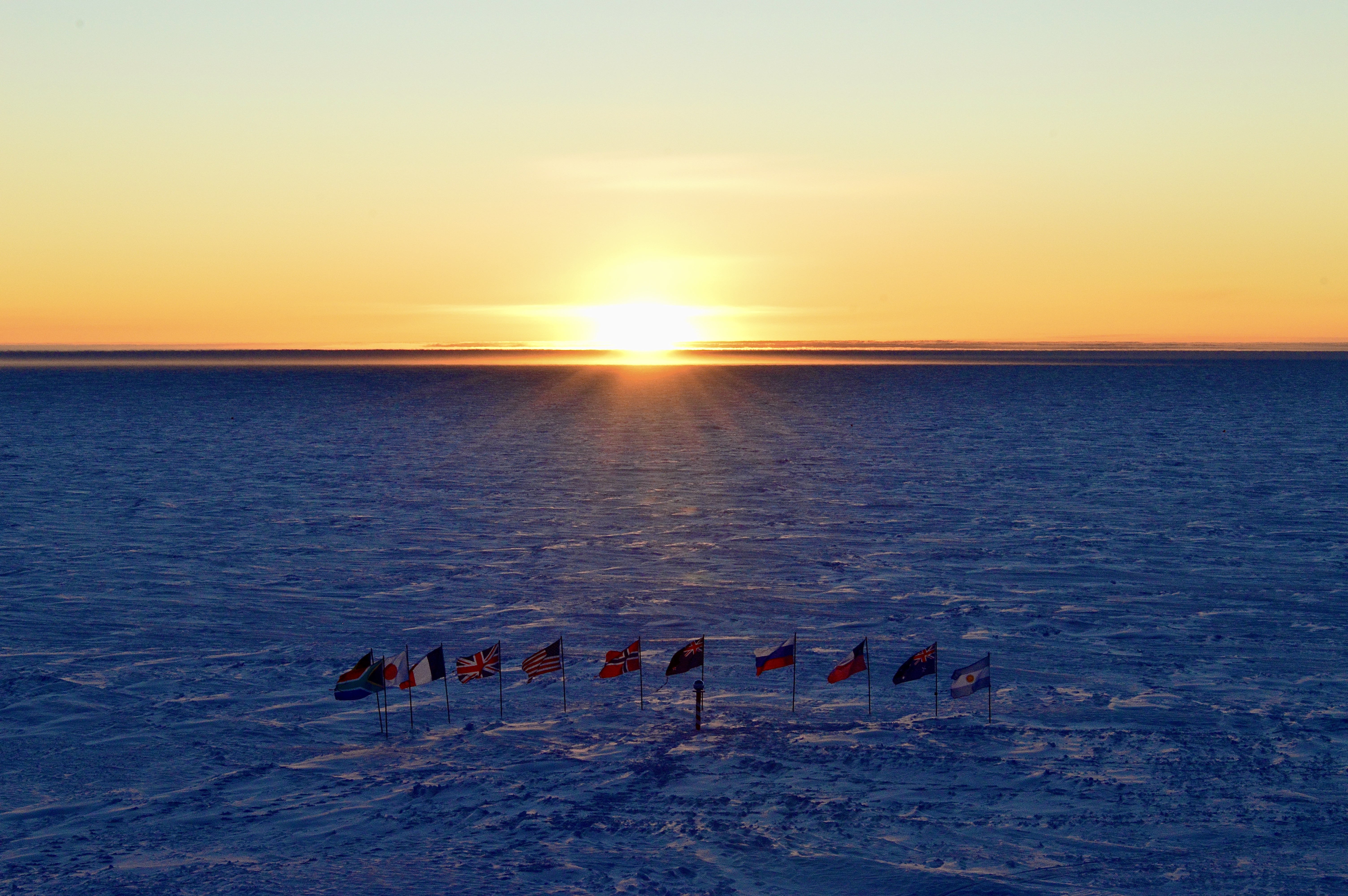 Grouping of flags on snowy landscape with sun setting in background