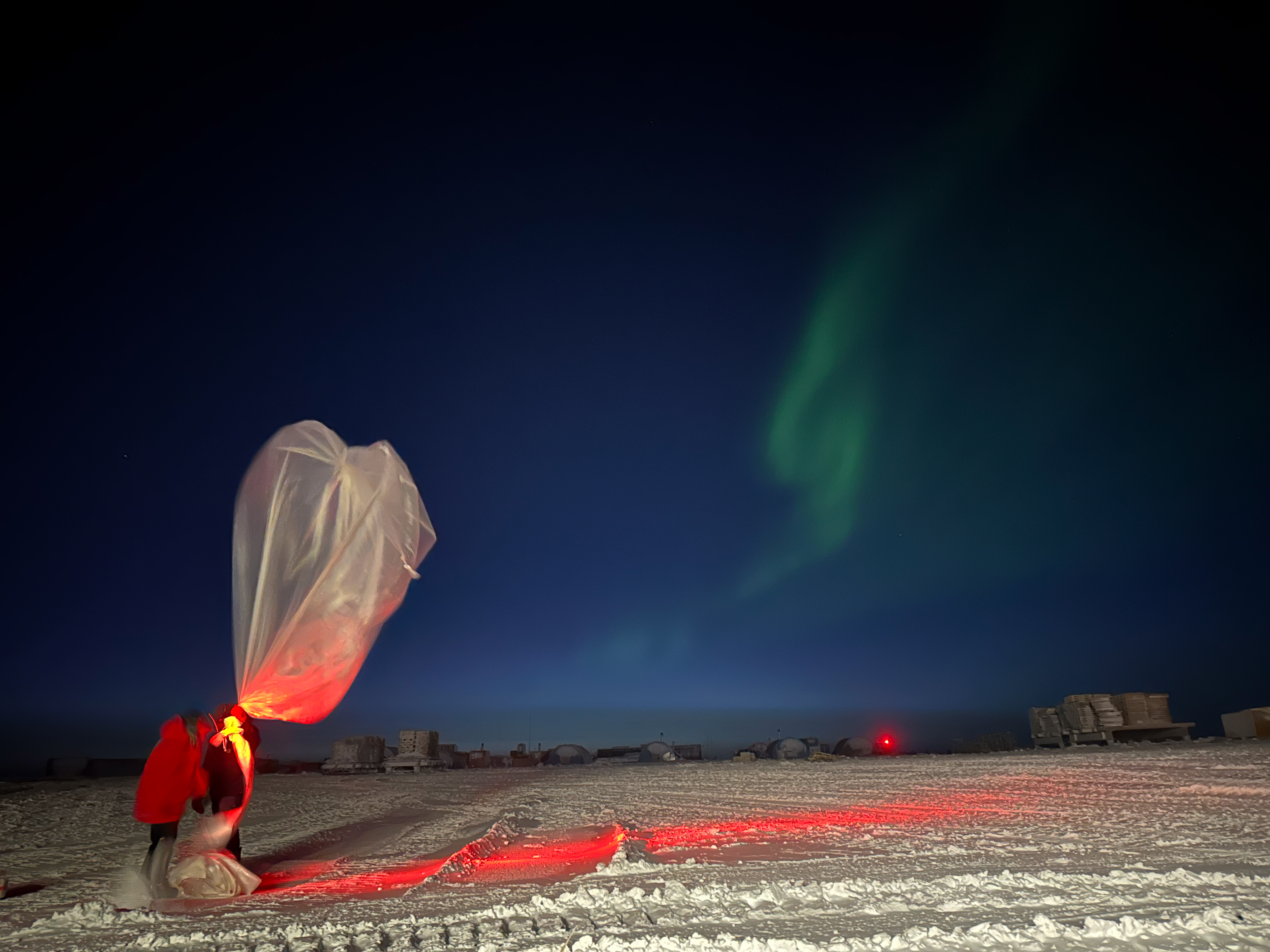 A weather balloon is inflated against a dark blue night sky