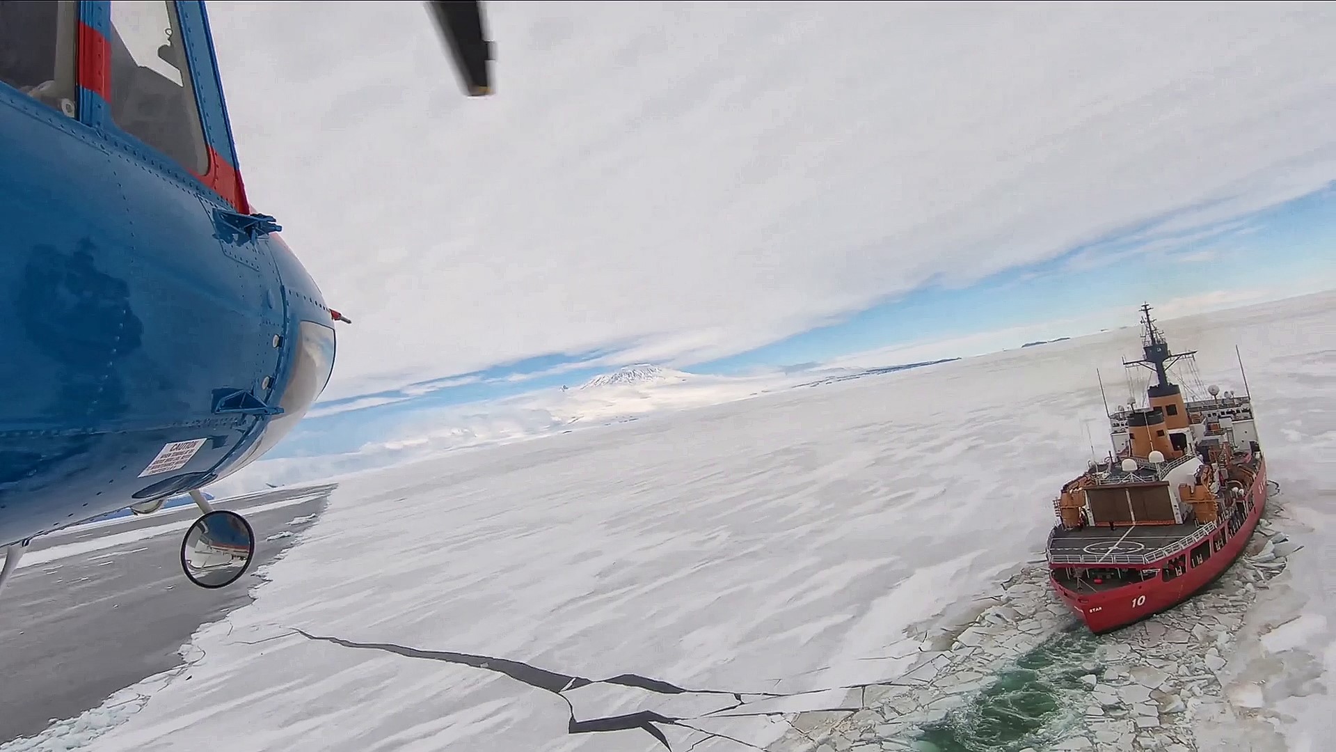 The nose of a helicopter overlooks ship in sea of ice.