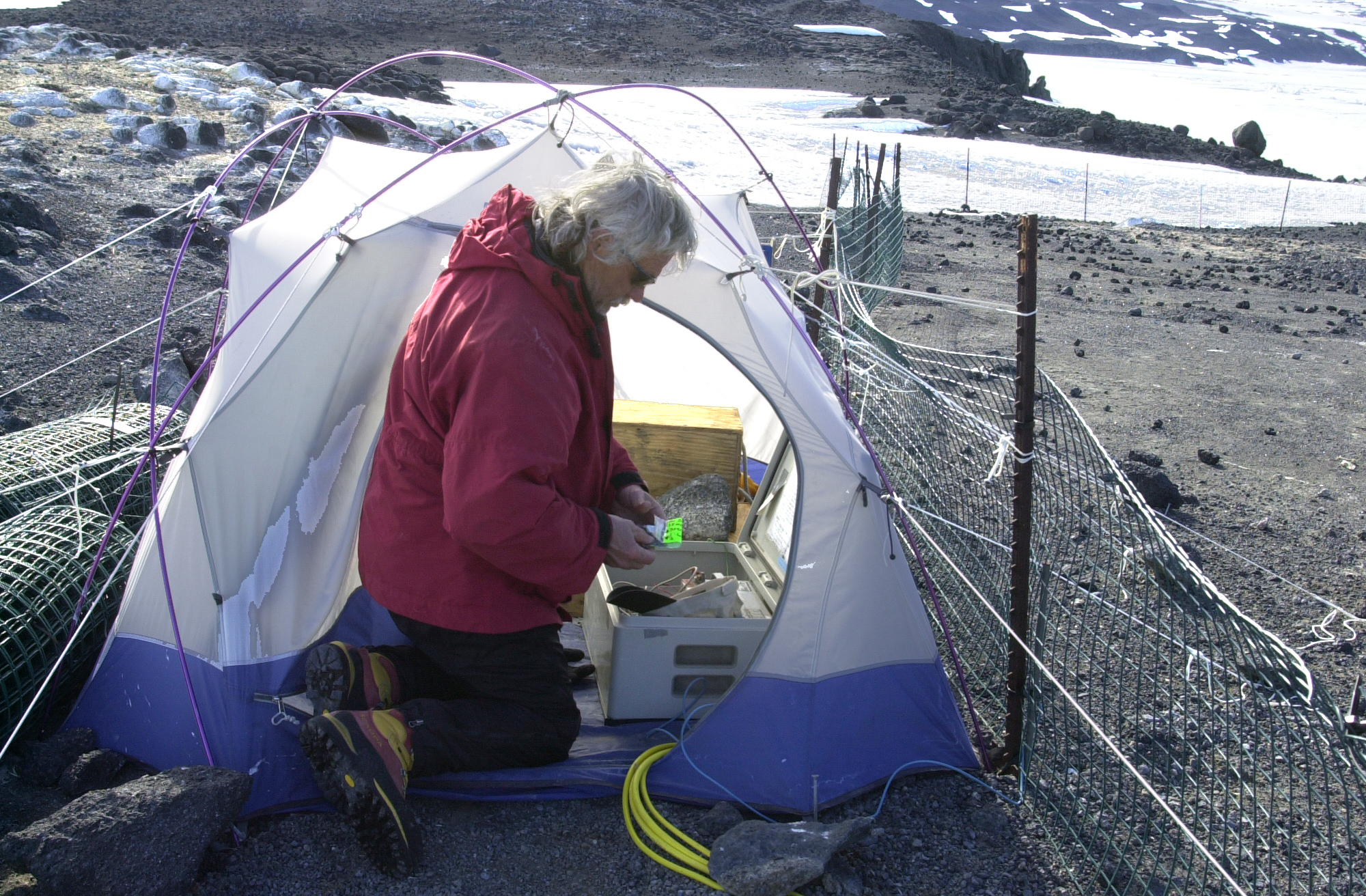 Man kneels in front of tent.