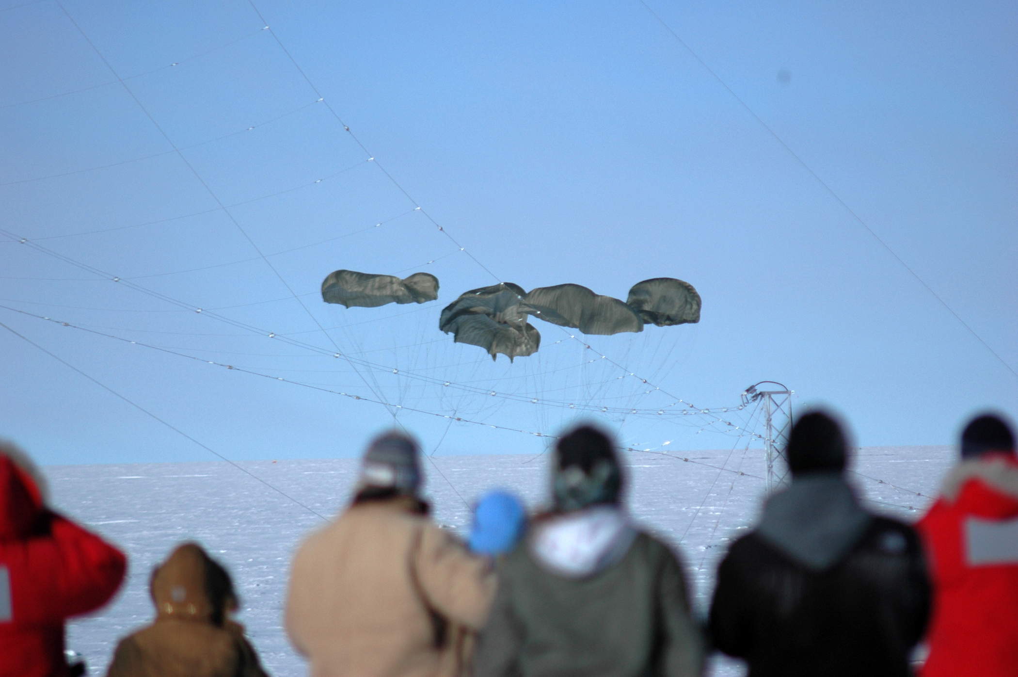 People watch parachutes descend to the ice.