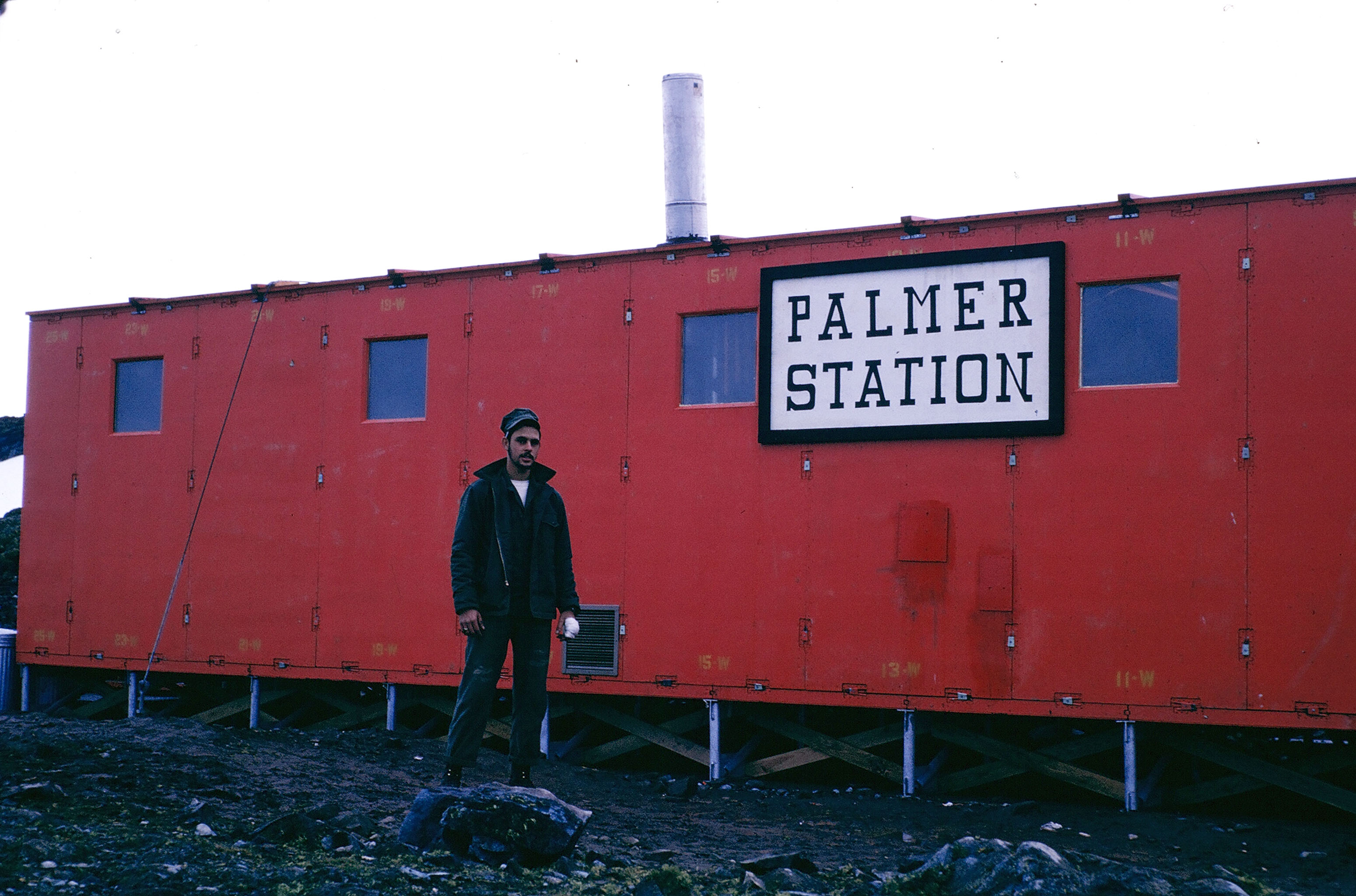 Person stands in front of red building.