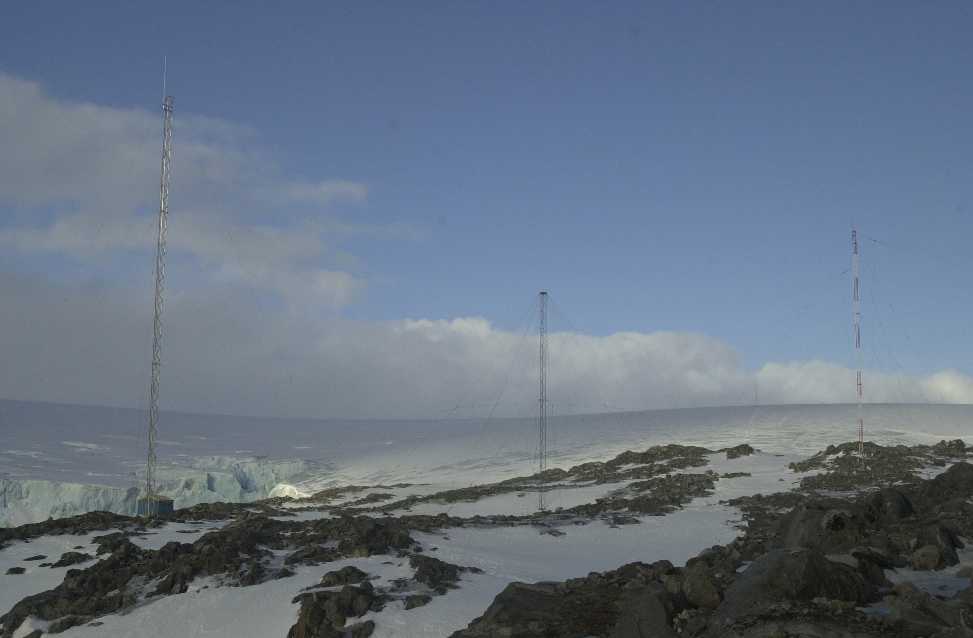 Three antenna towers in front of glacier