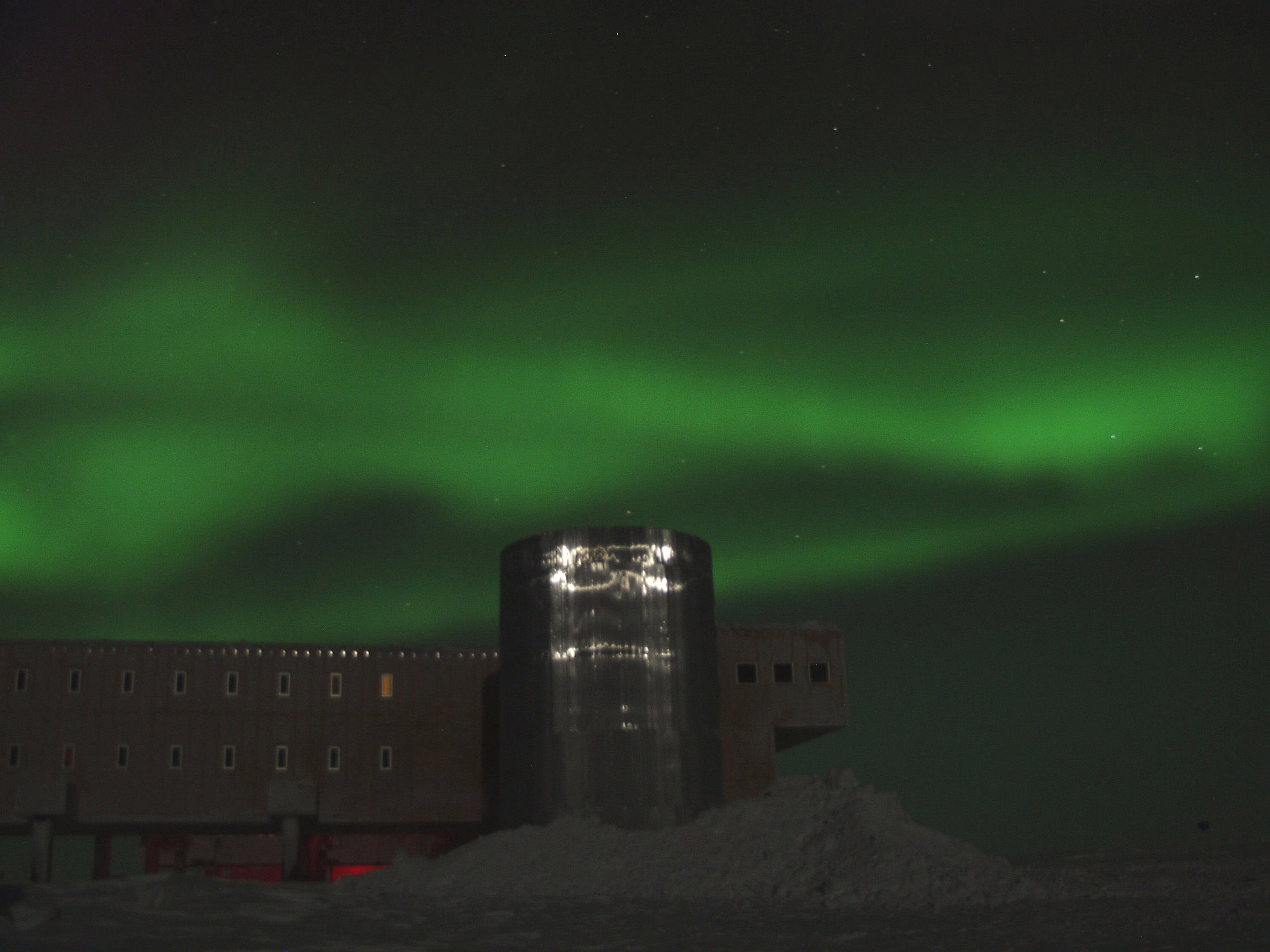 Green lights in night sky above a building.