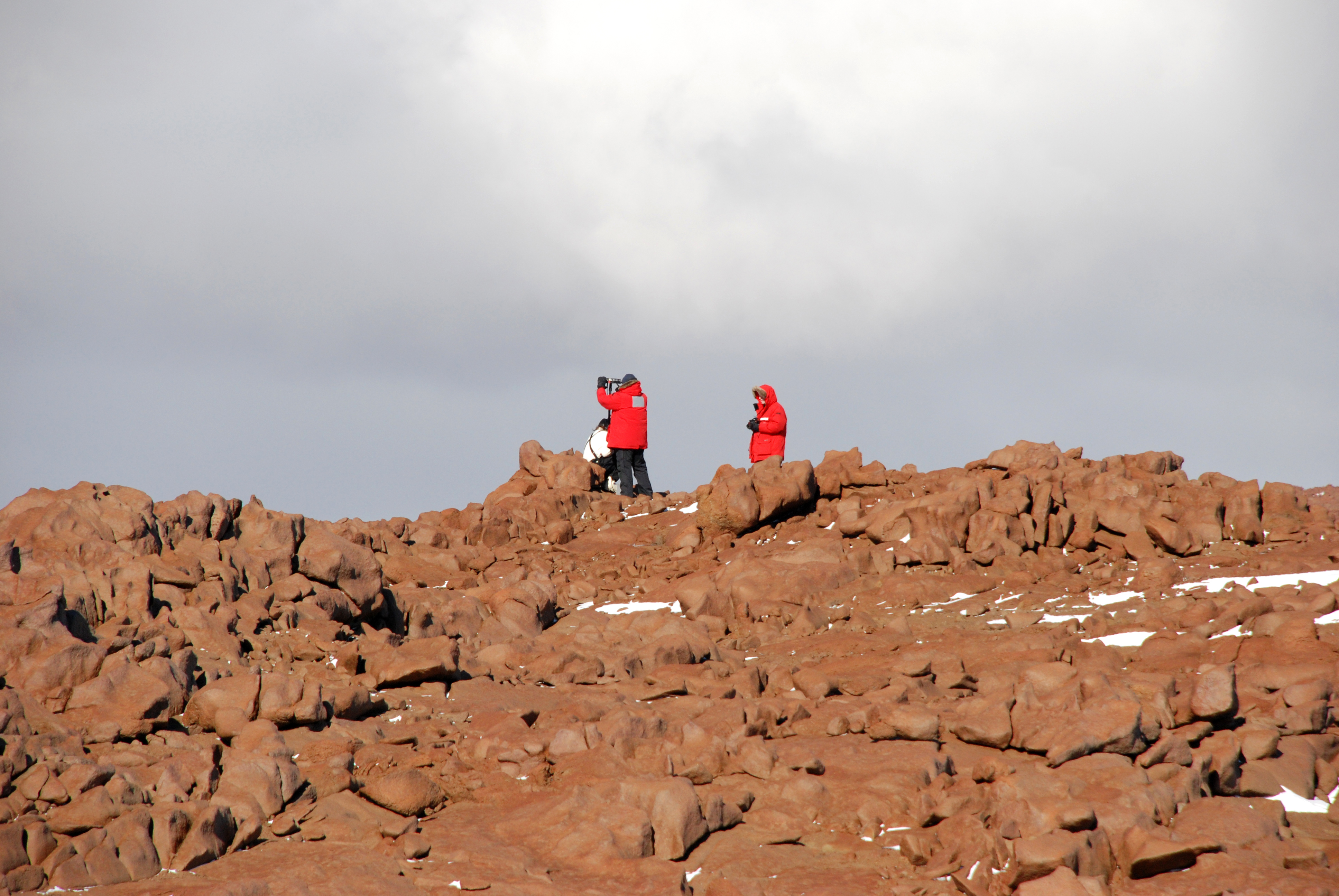 People in red parkas on a rocky terrain.