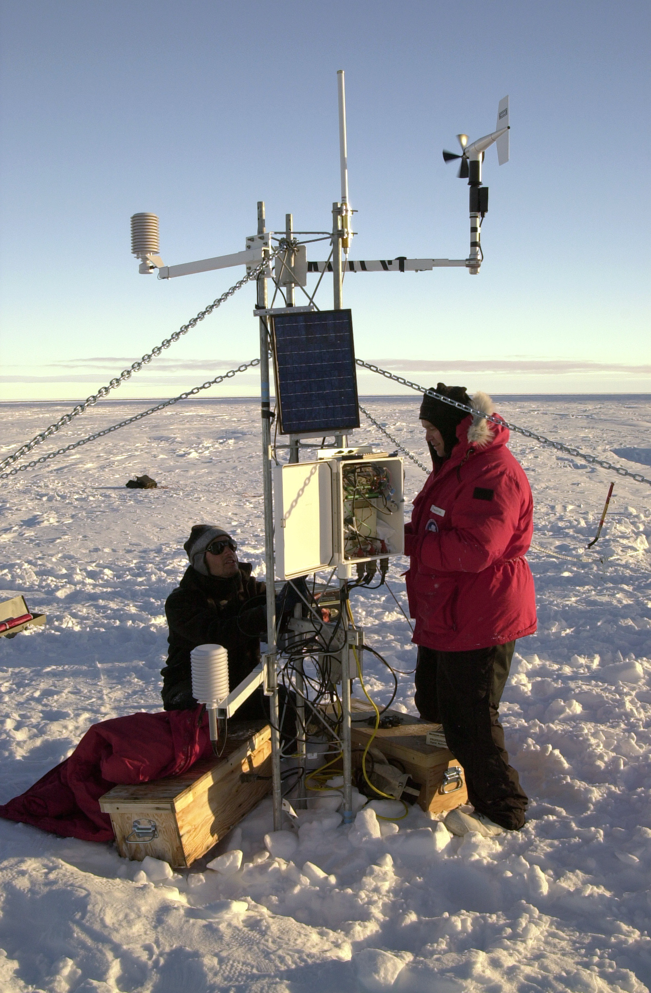 Two people work on a small receiving tower.