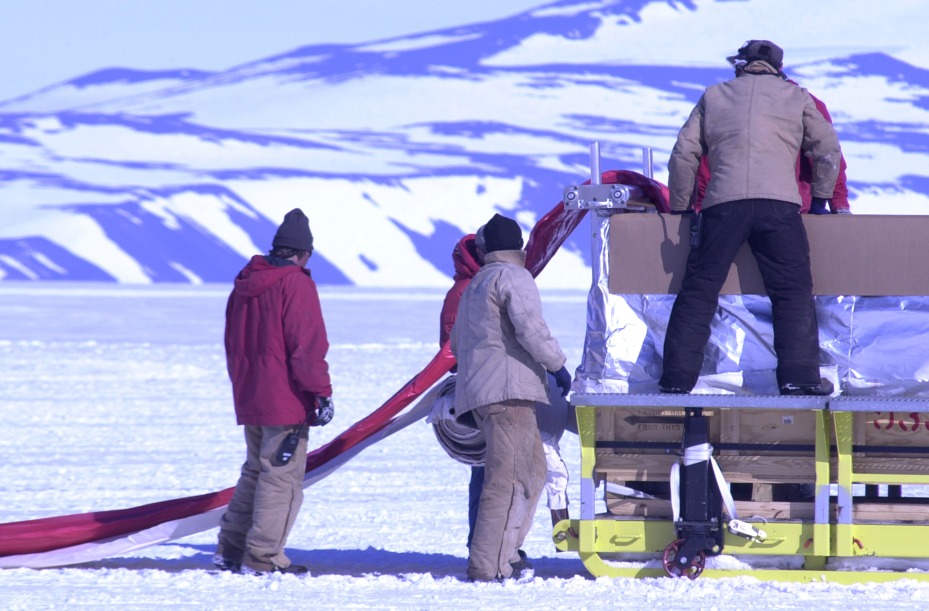 People stand on snow with a piece of equipment.