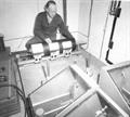 A man squats next to a scientific machine.