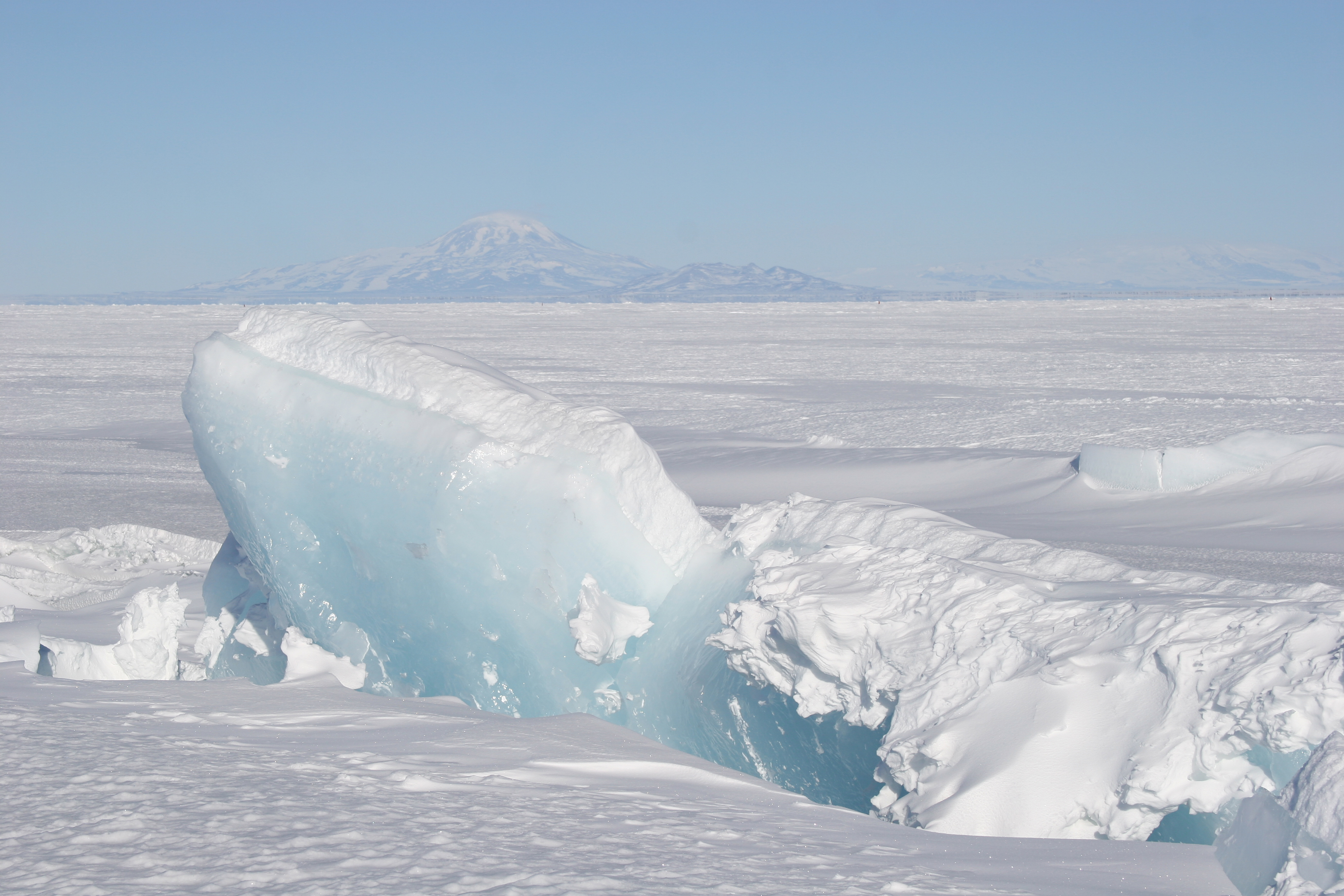 Blue, snow-covered ice portruding out of surrounding snow.