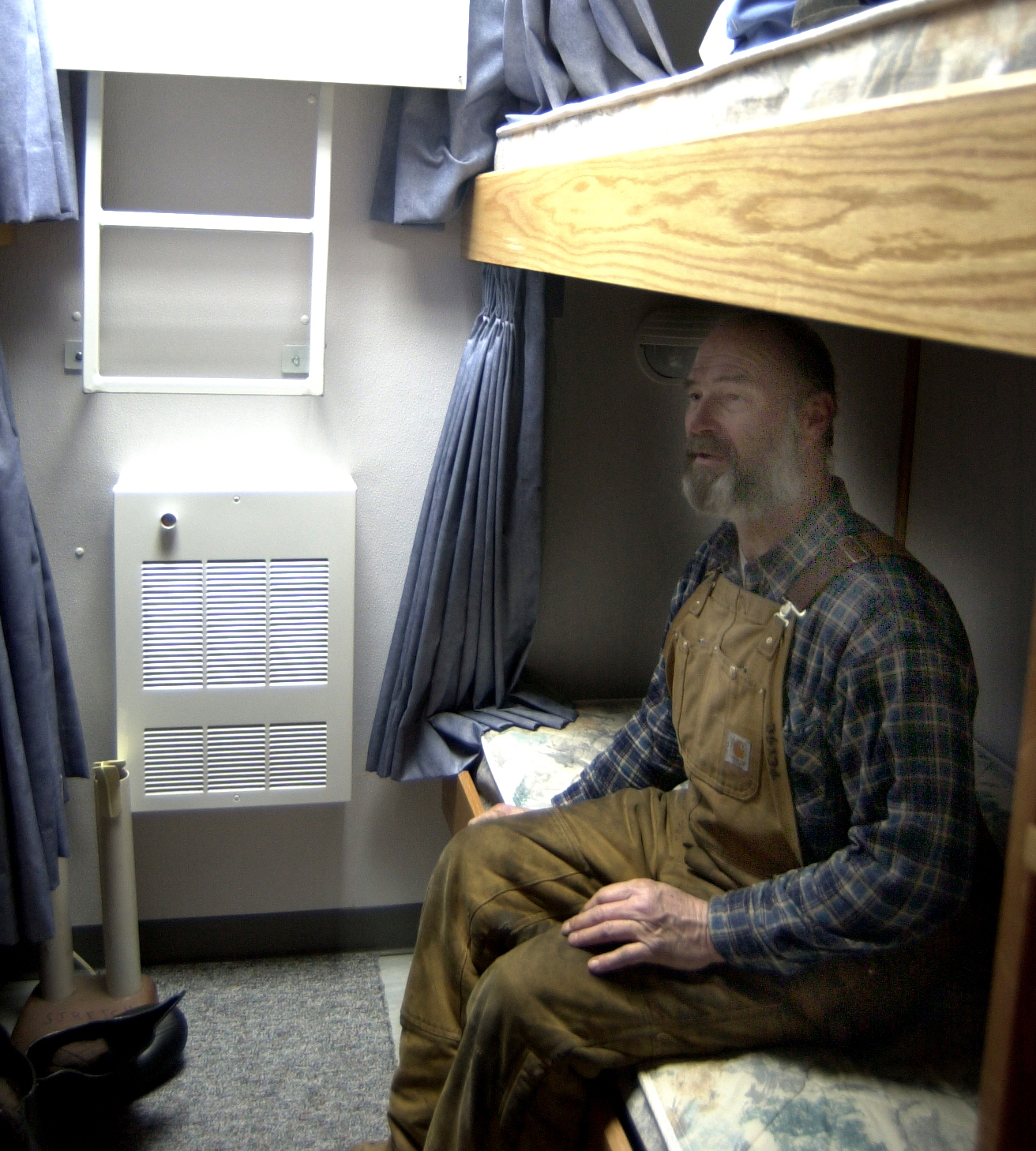 A man sits on the bottom bunk of a bunk bed.