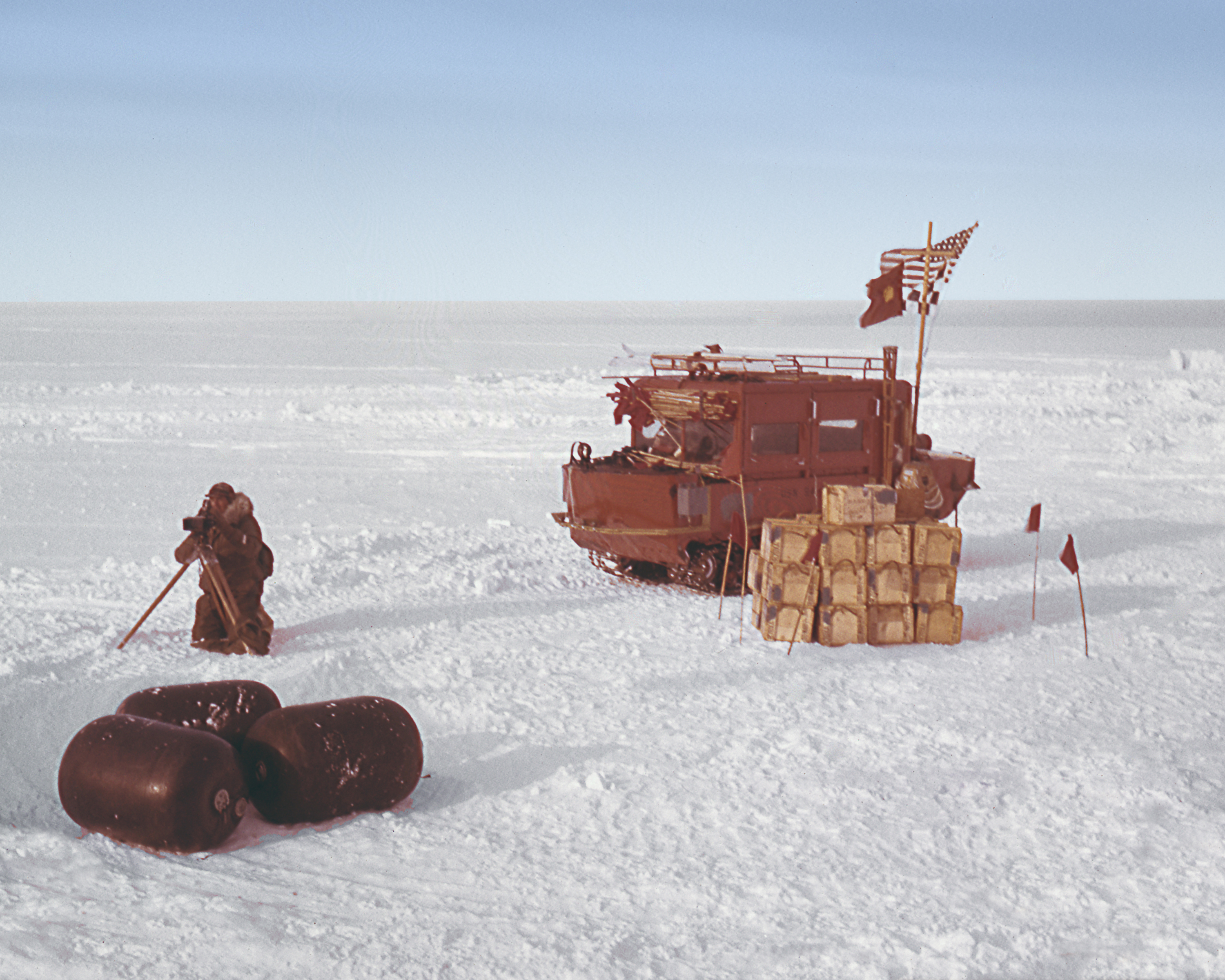 Tracked vehicle, cargo, and a man on snow.