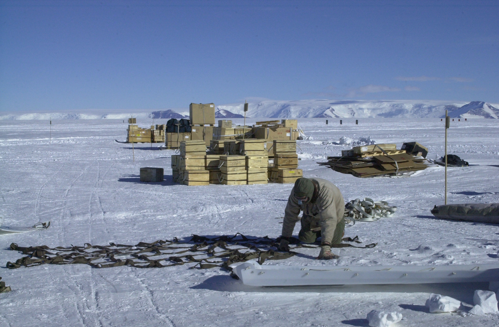 A man arranges a cargo net on snow.