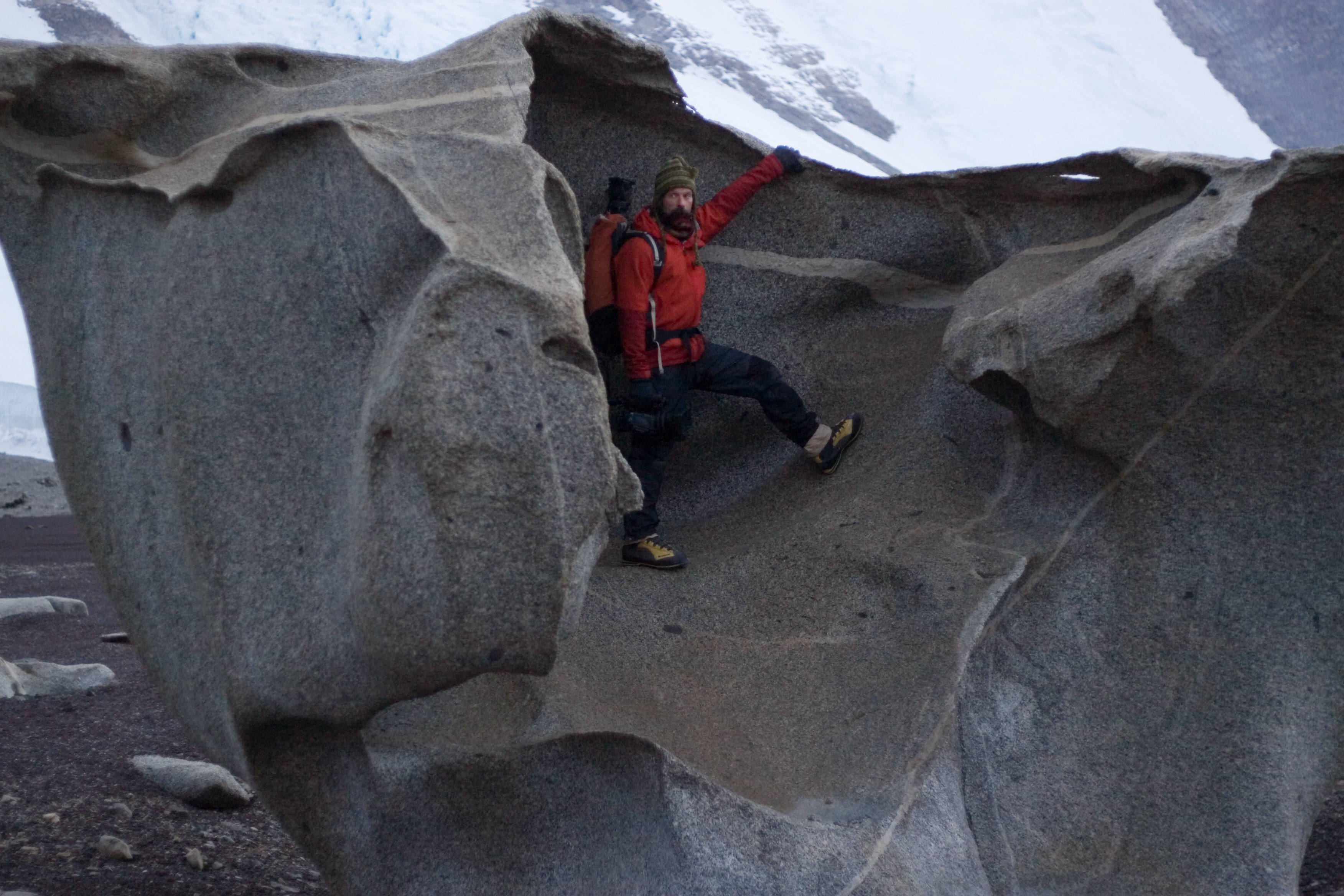 Man stands inside large boulder.