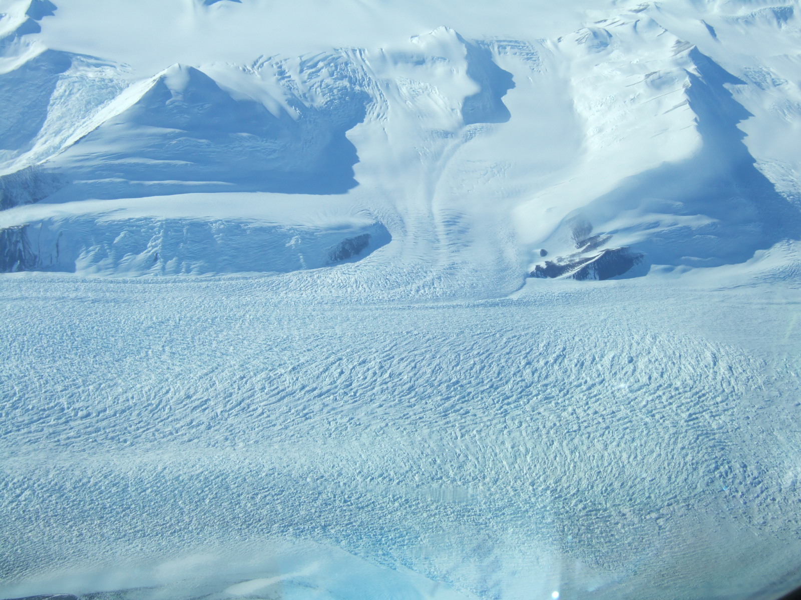 Aerial view of snow, mountains, and crevasses.