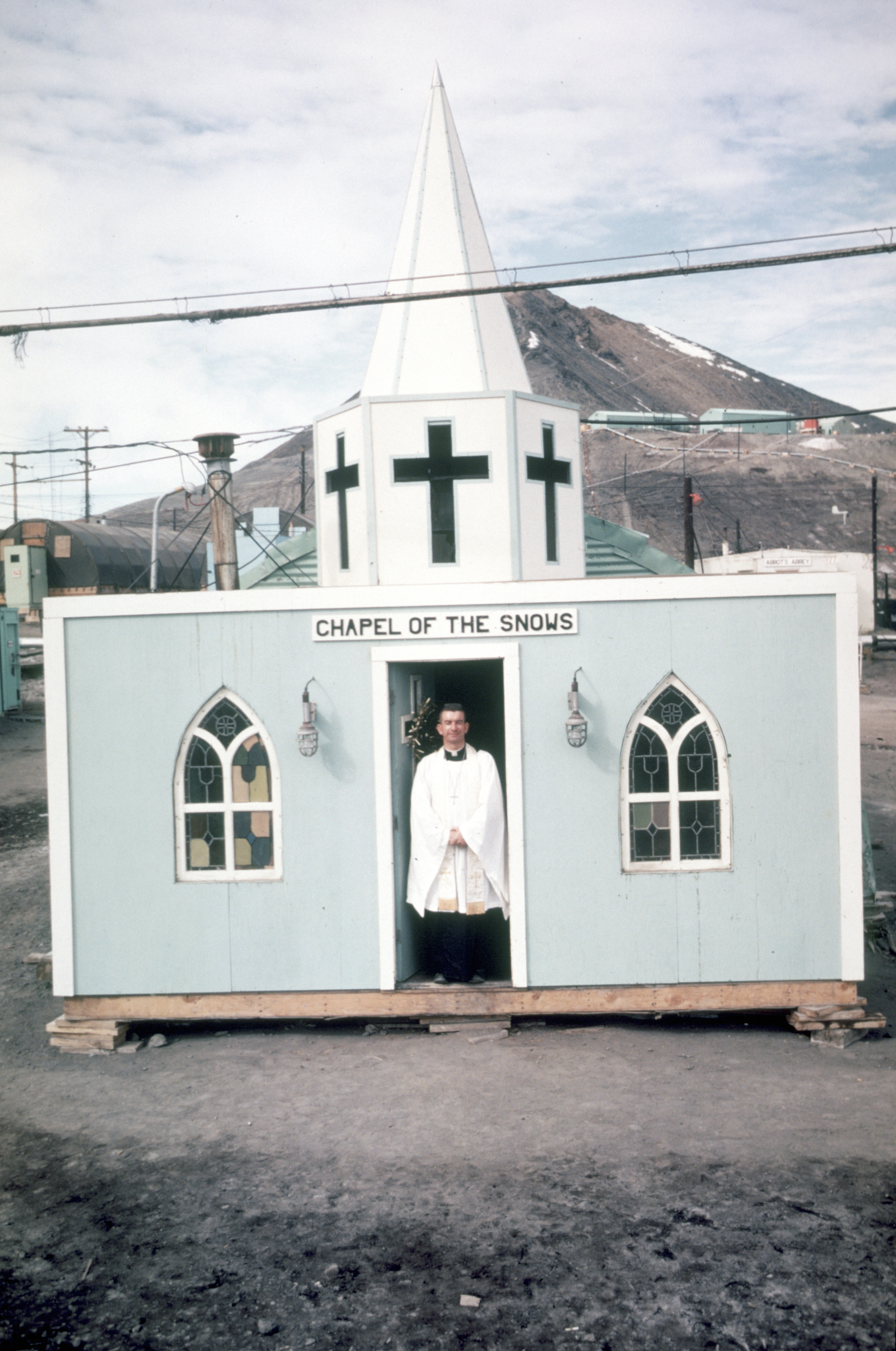 A minister stands in the doorway of a small church.