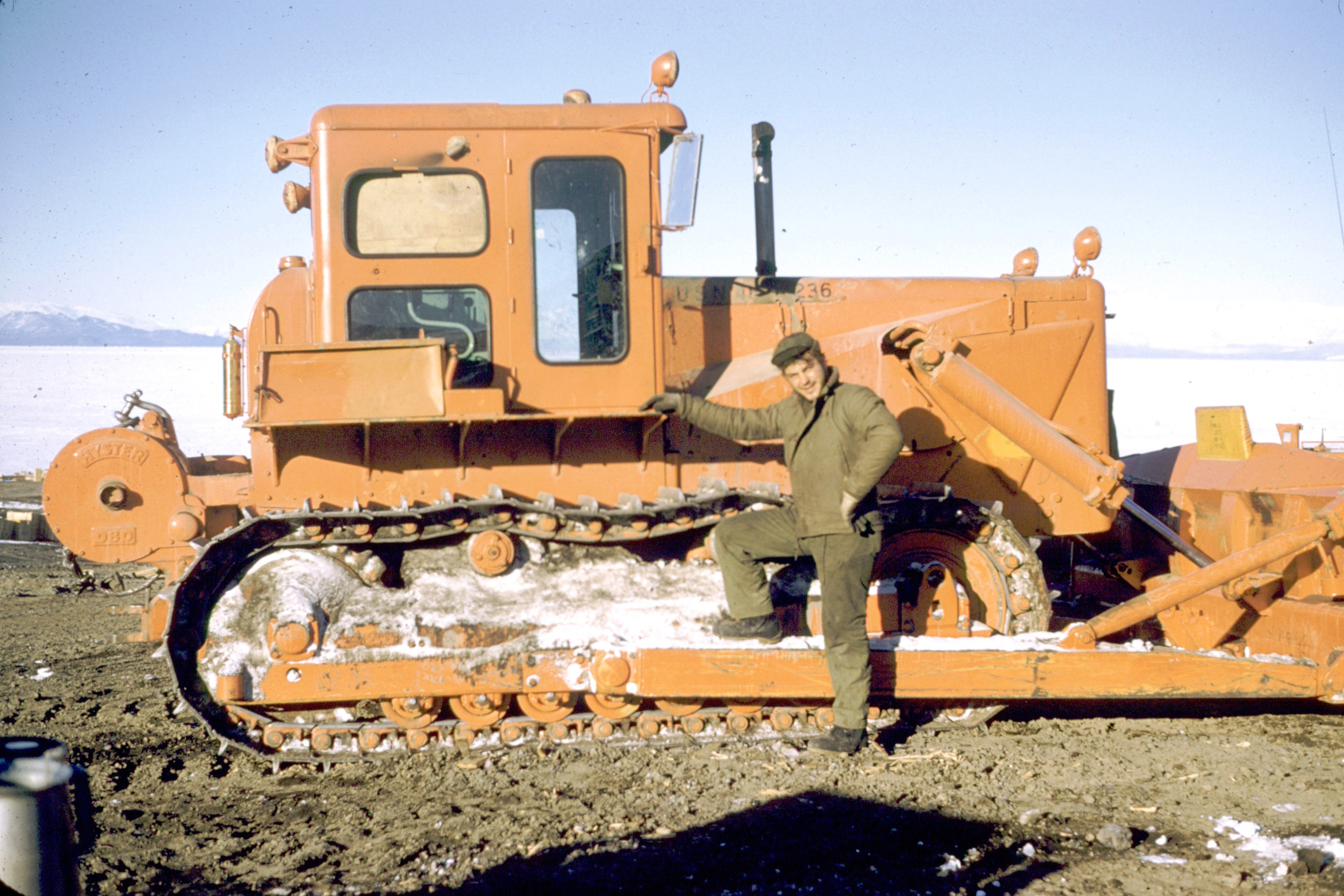 A man leans next to a Caterpillar tractor.