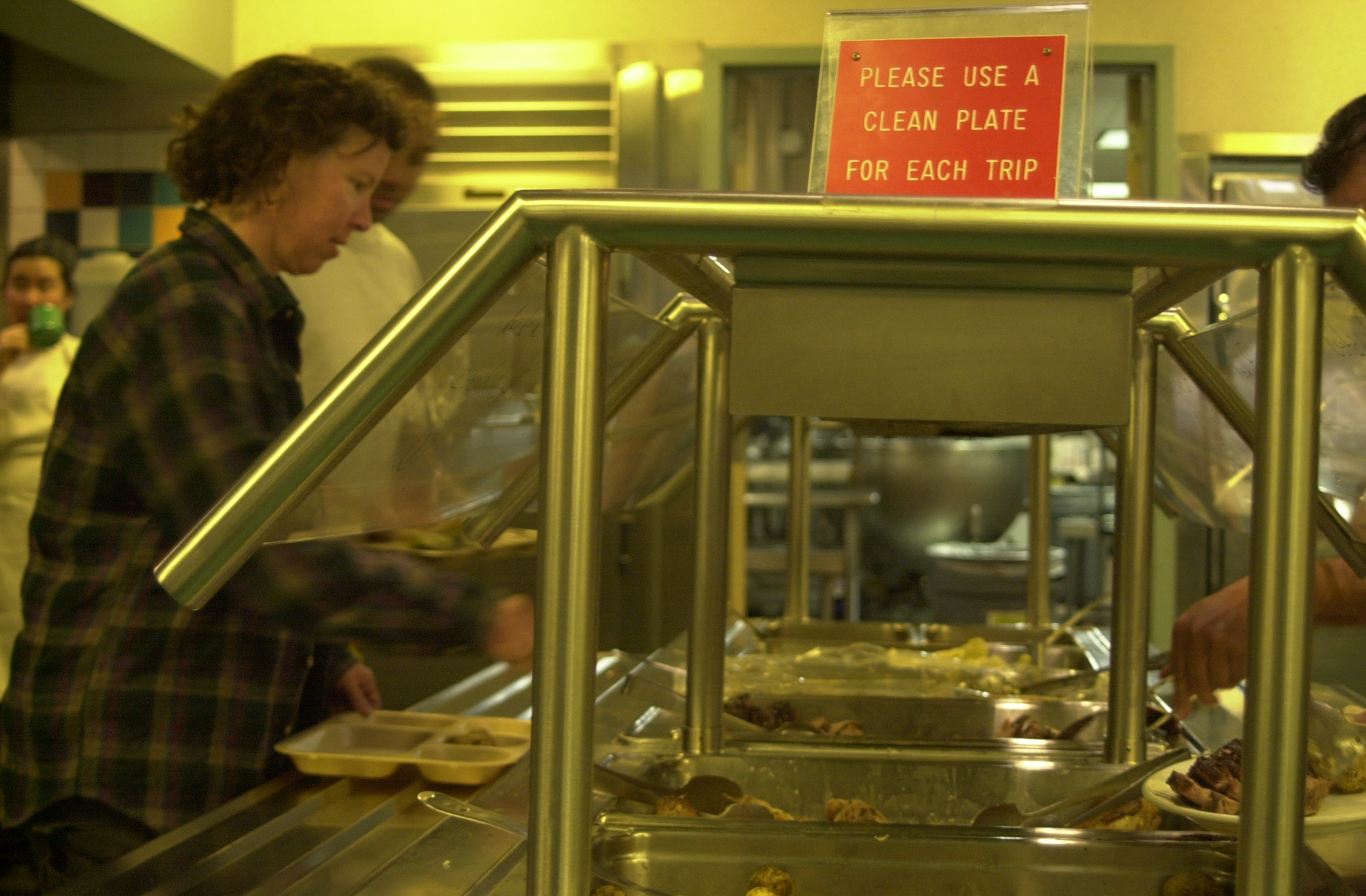 A woman fills a plate with food.