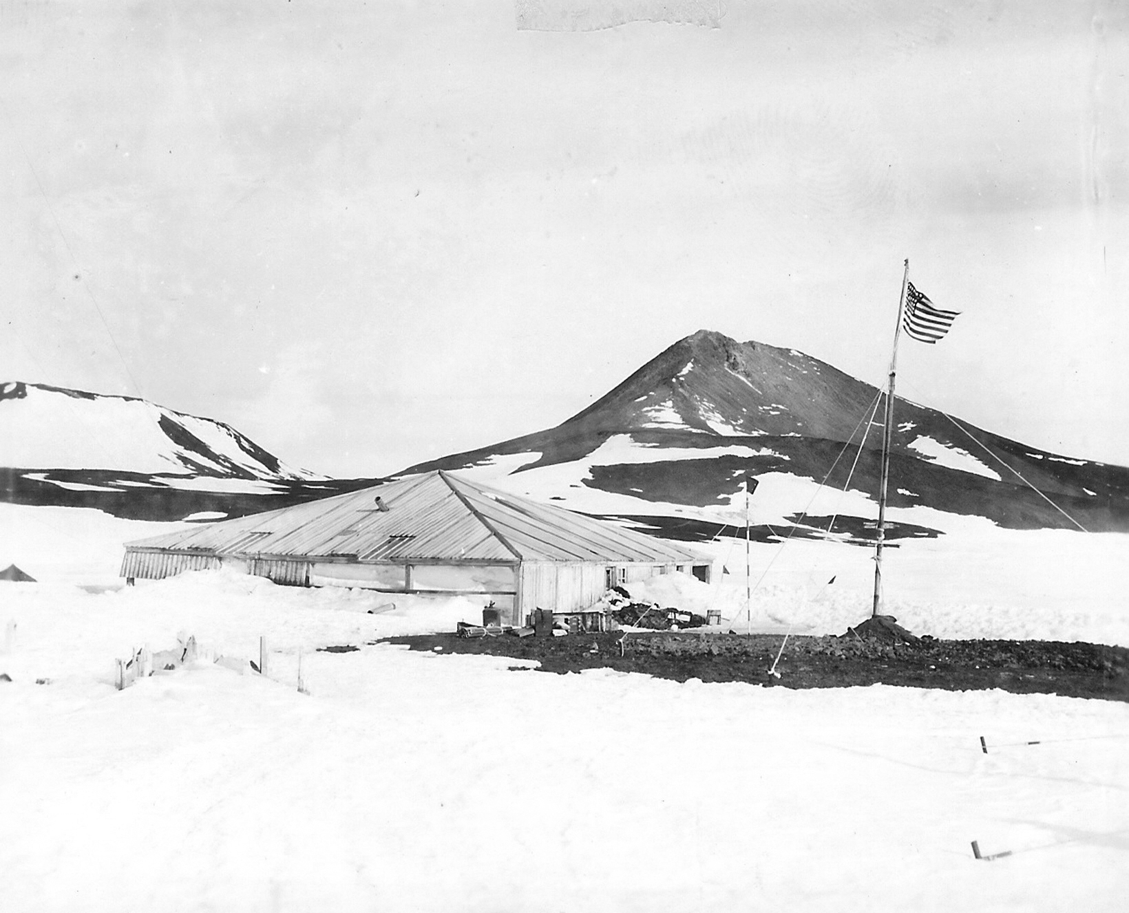 American flag flies near a wooden hut.