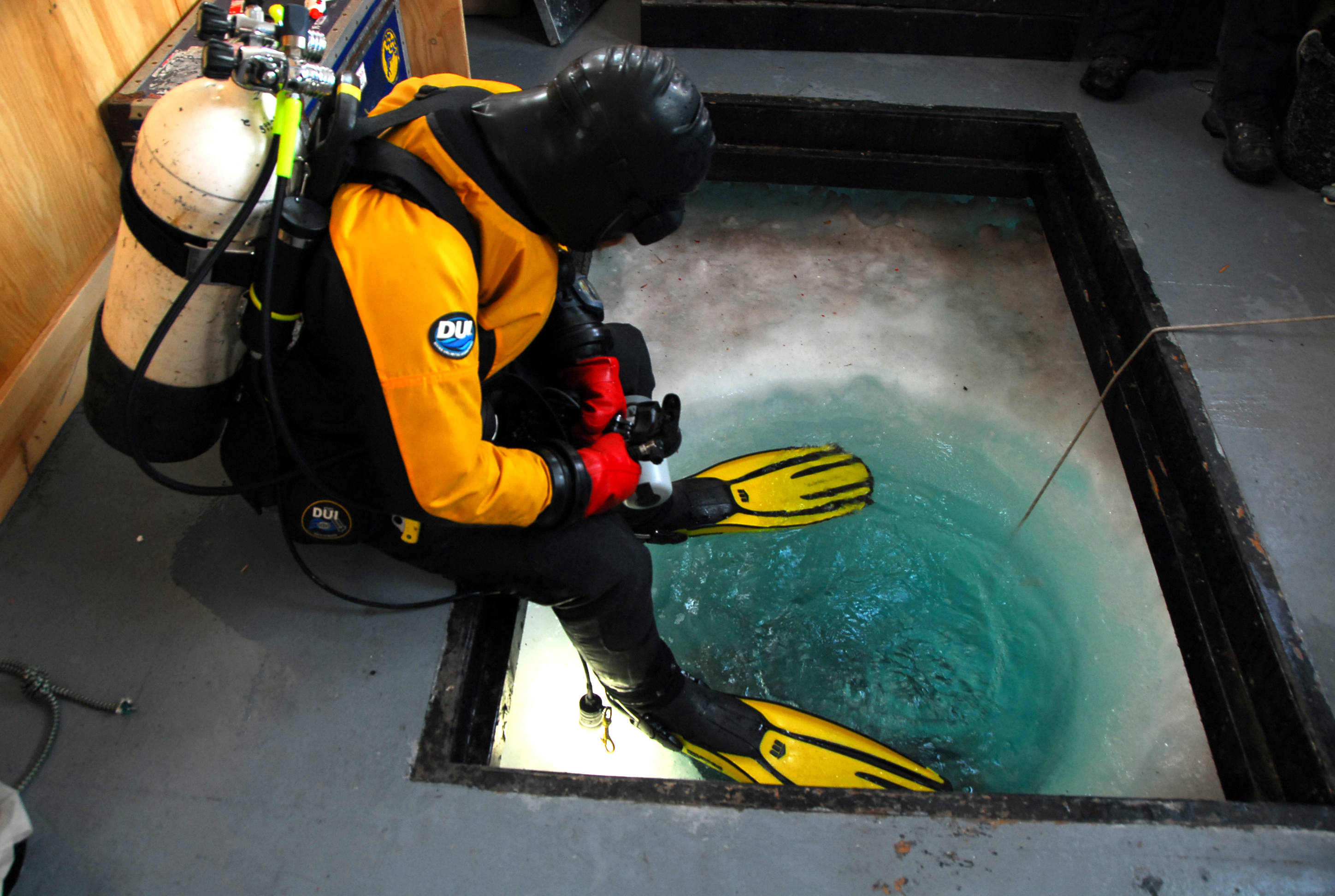 A diver prepares to enter the water through a hole in the floor.