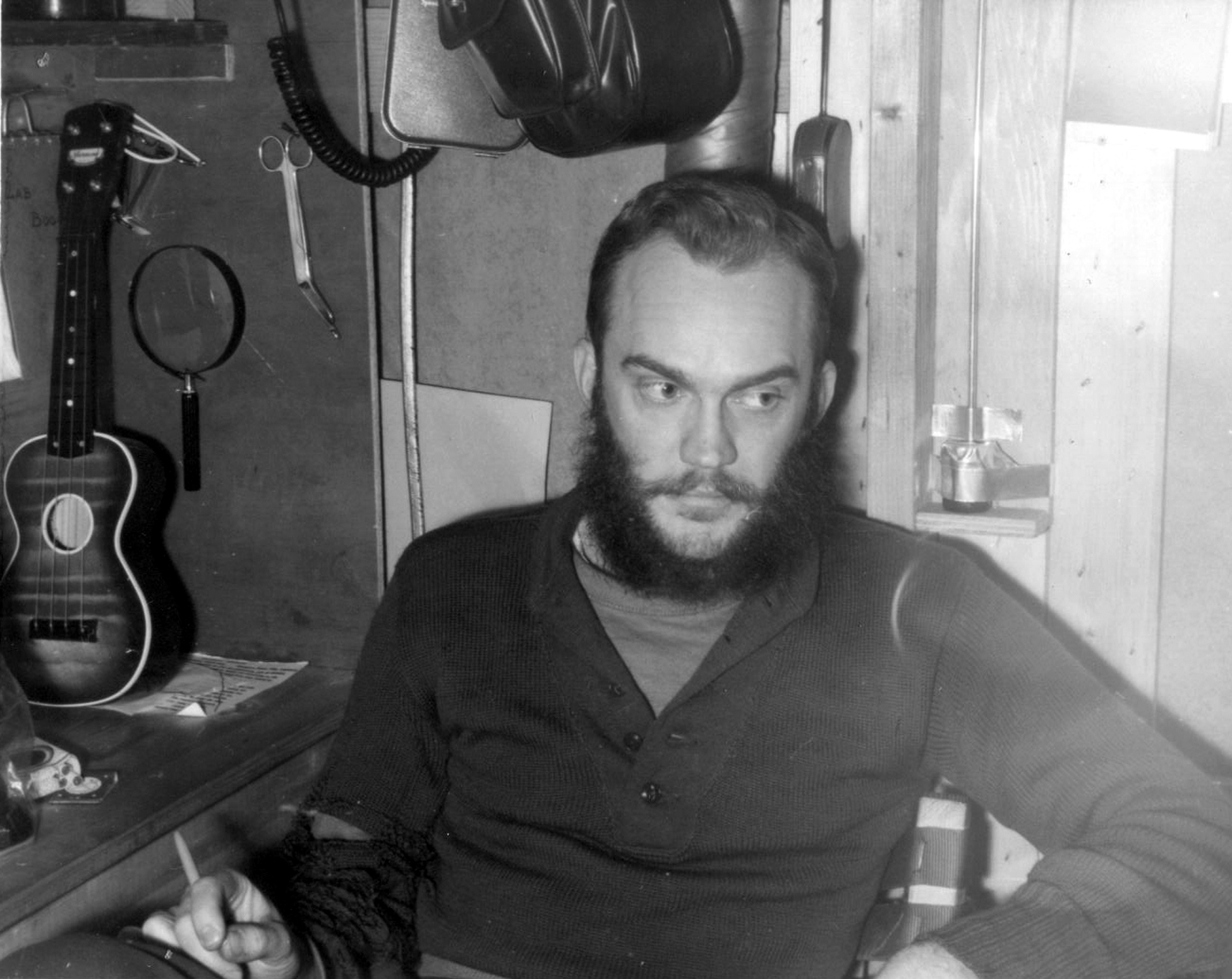 A small instrument stands next to a man with a beard.