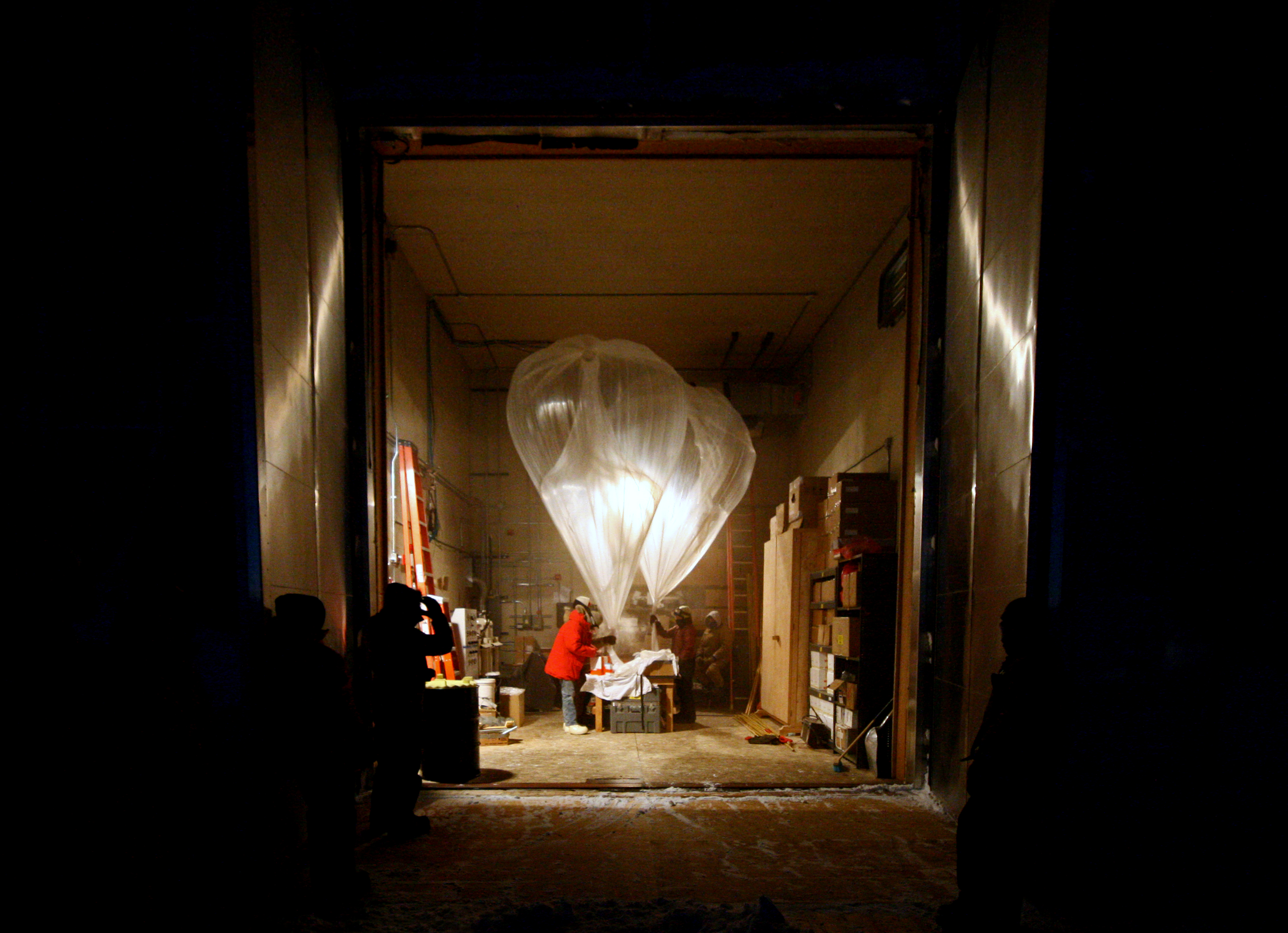 People with a large balloon inside a building.