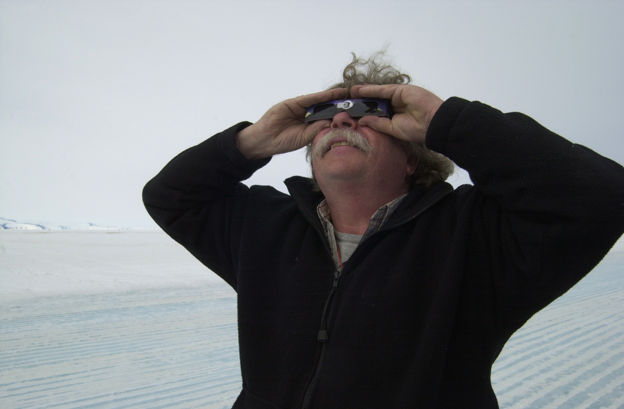 A man holding dark glasses over his eyes.