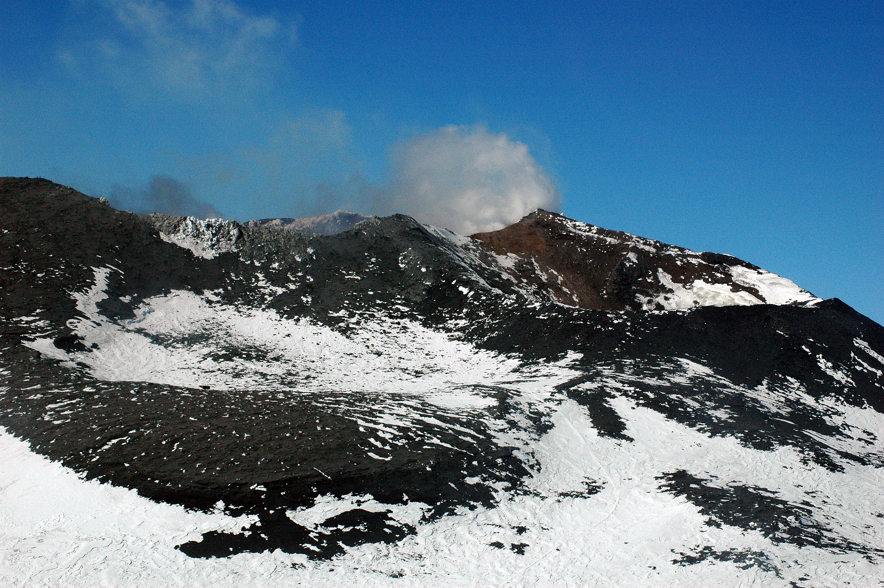 Smoke billows from the crater of a volcano.