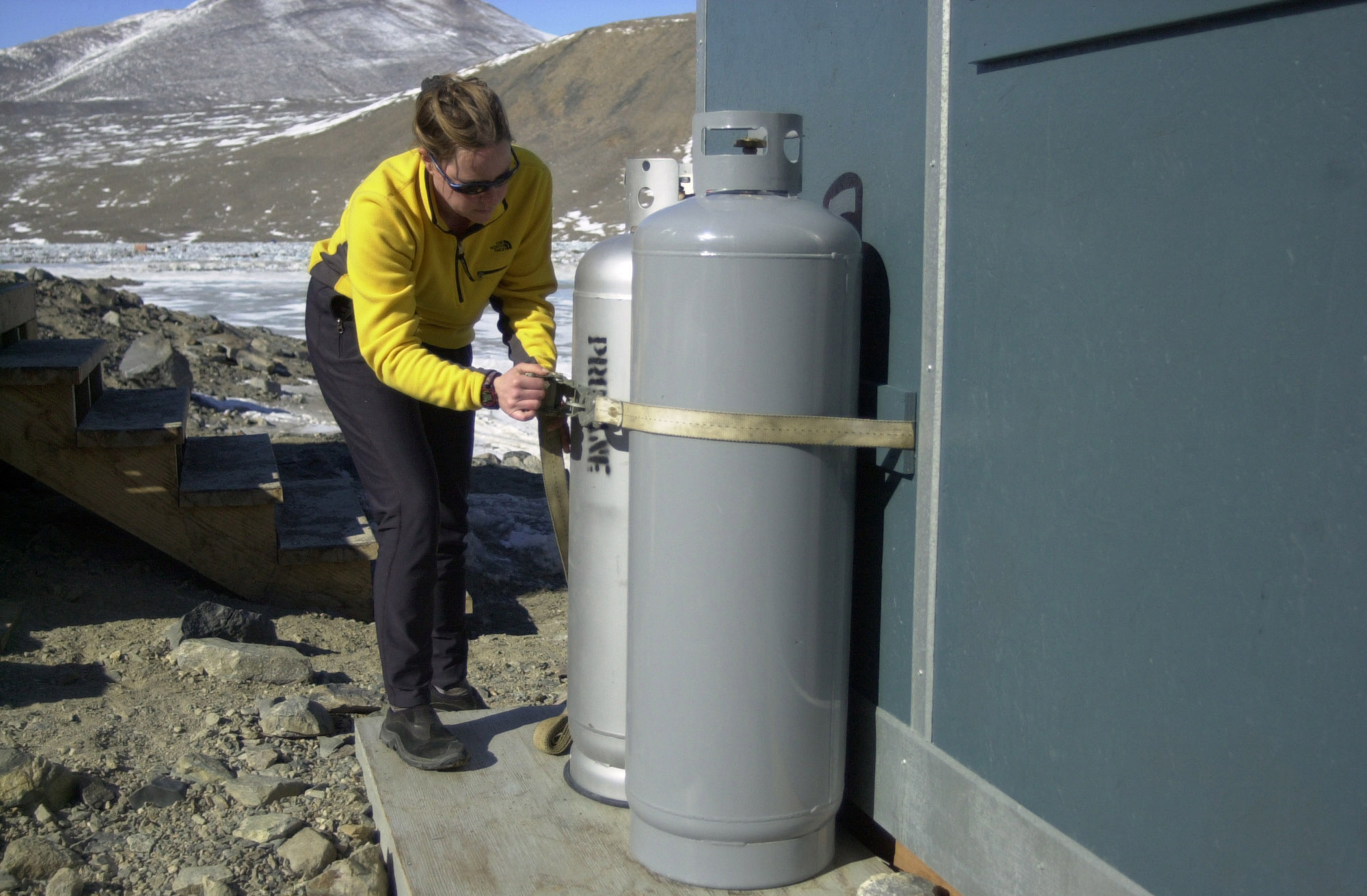 A woman adjusts straps around two propane gas tanks.