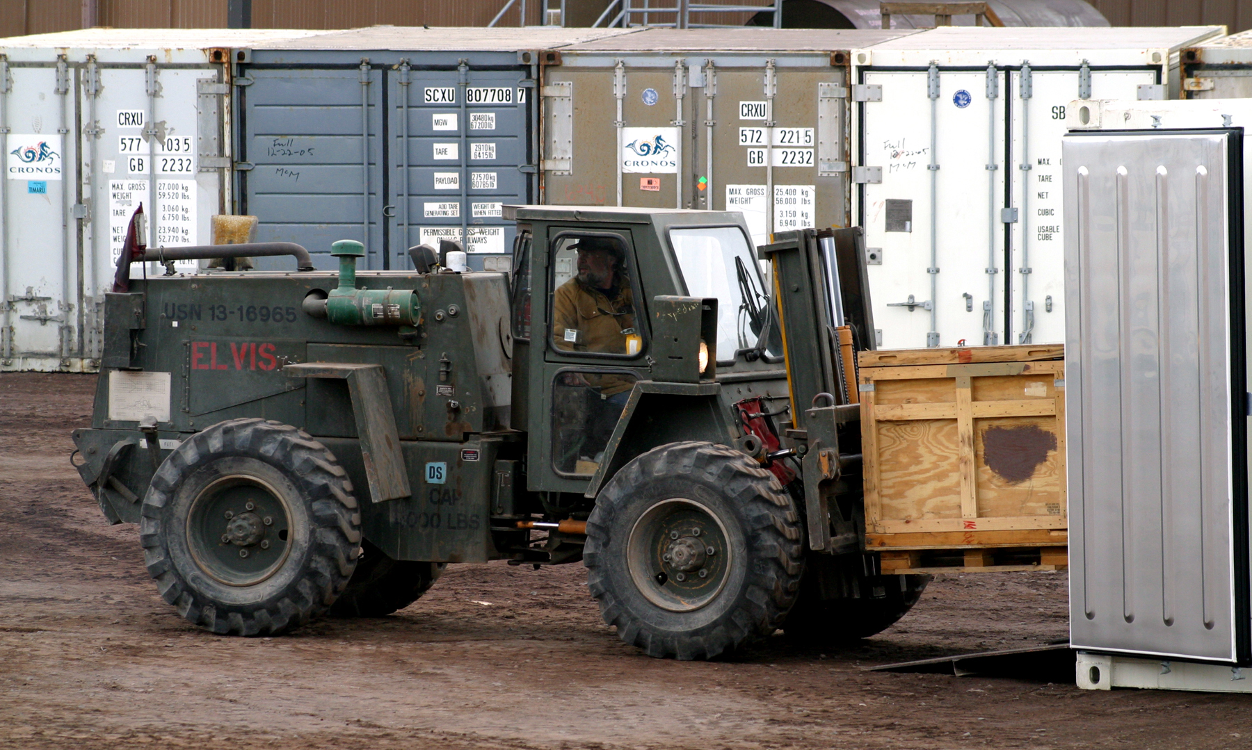 A forklift carries a wooden box.