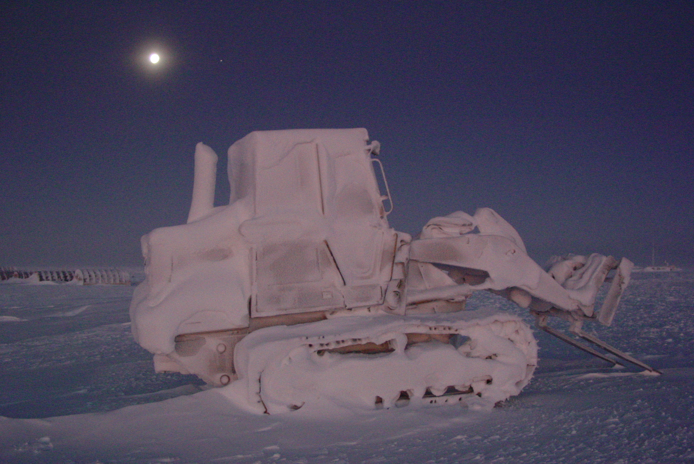 A tractor with a loader is encased in snow.