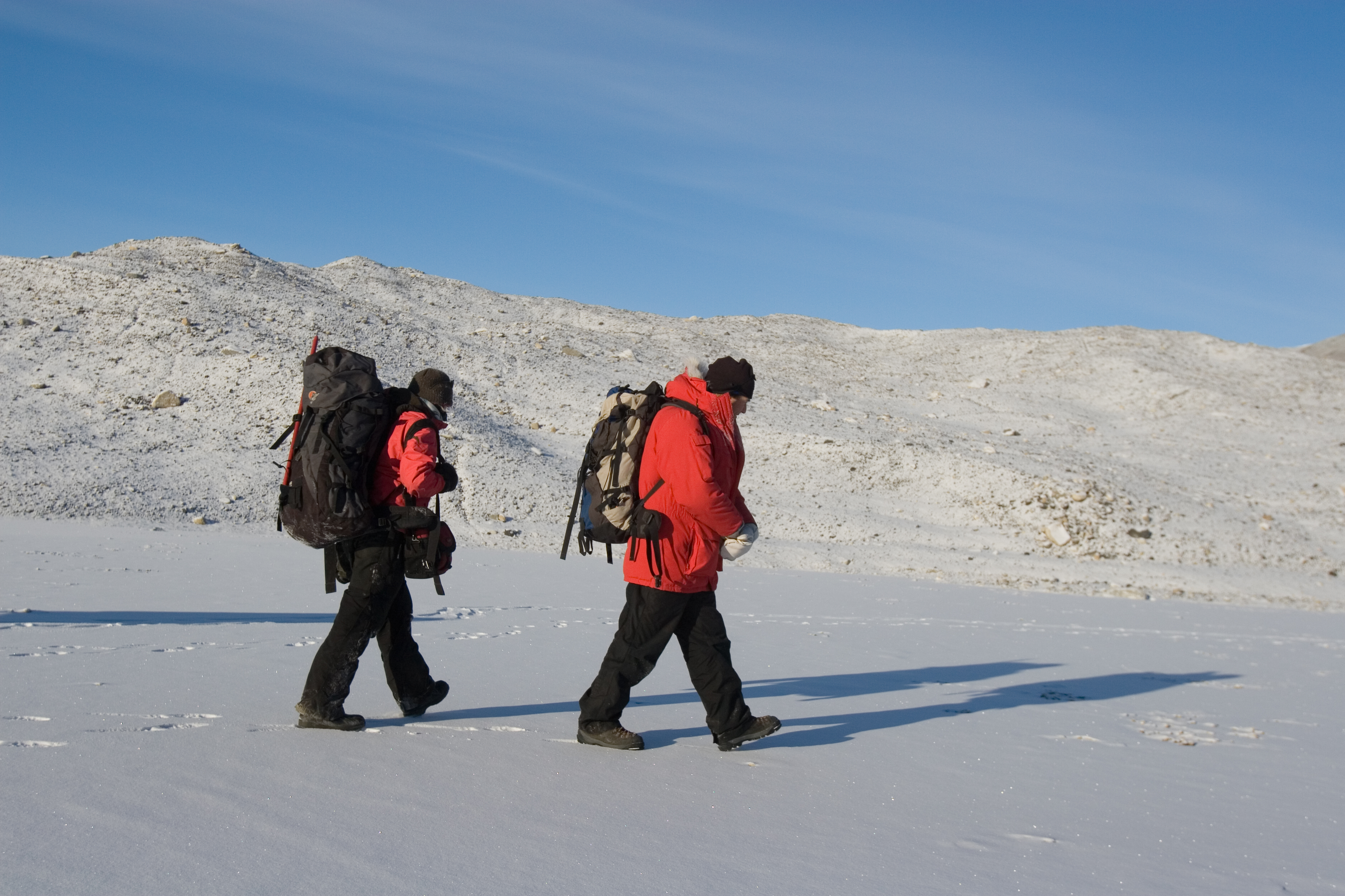 Two people walk on snow.